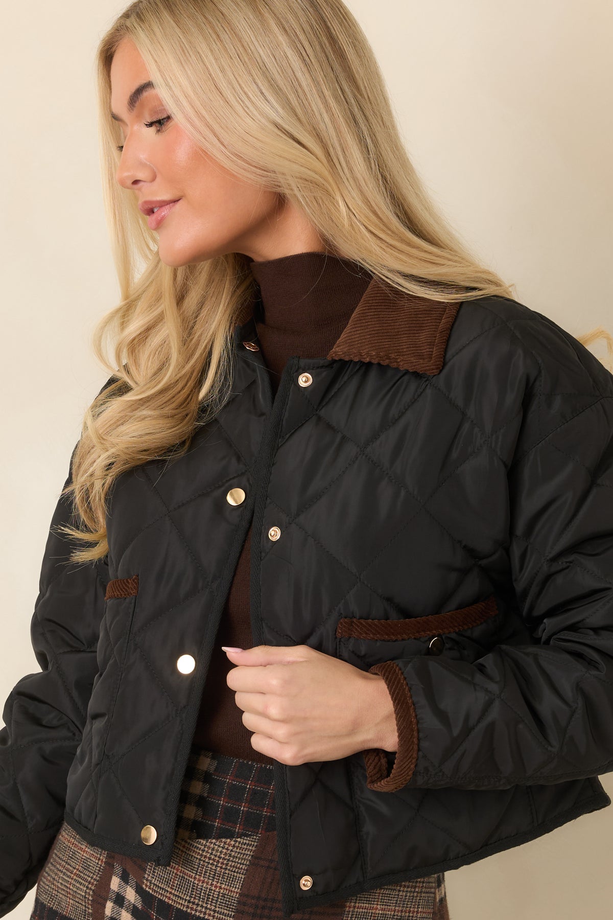 Front snap closures run down the quilted jacket beneath the contrasting brown collar.