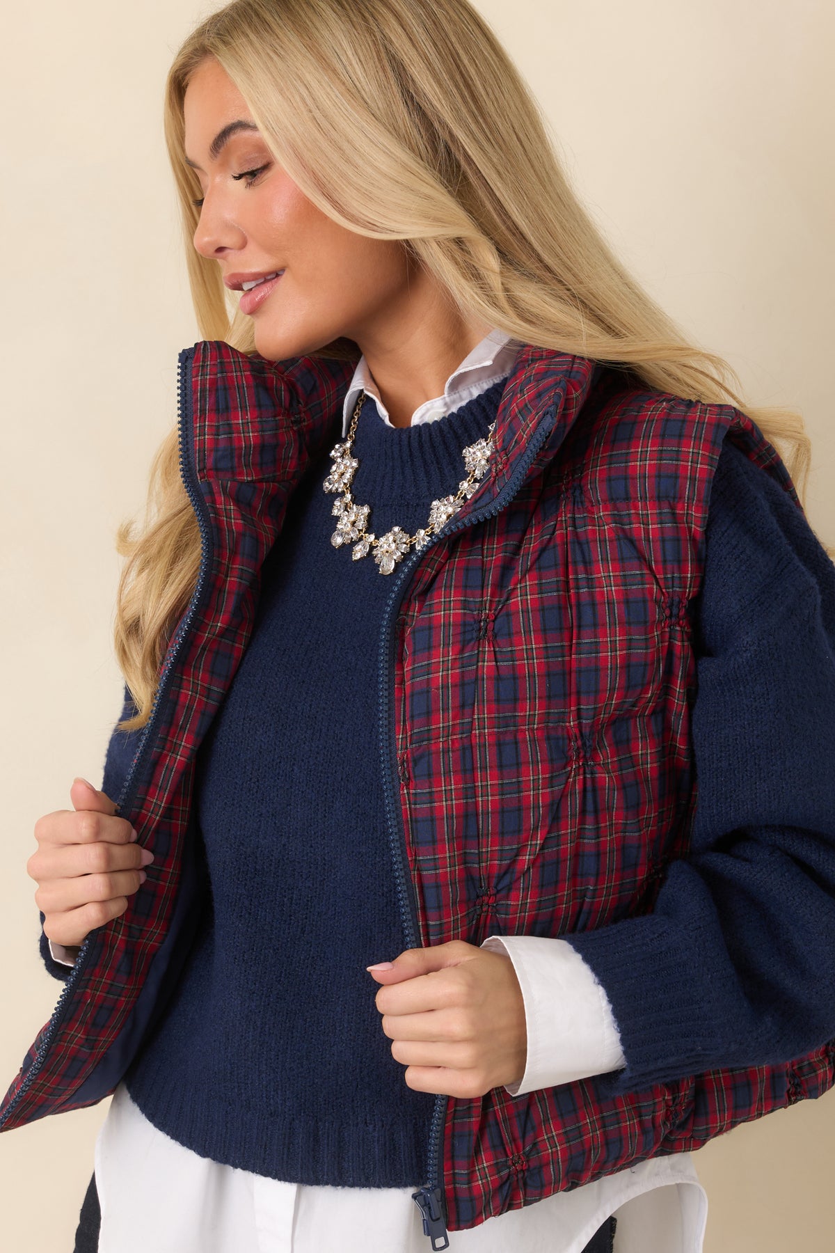 Navy zipper contrasts with the plaid fabric on the front of the quilted vest.