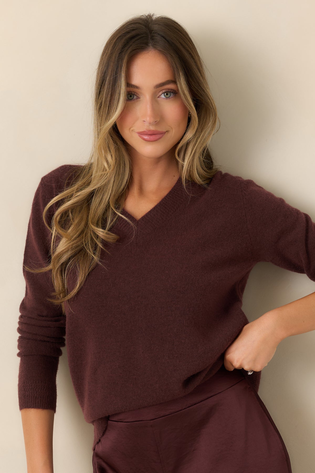 Muted plum-brown undertones enrich the deep raisin knit, complemented by ribbed detailing around the V-neckline.