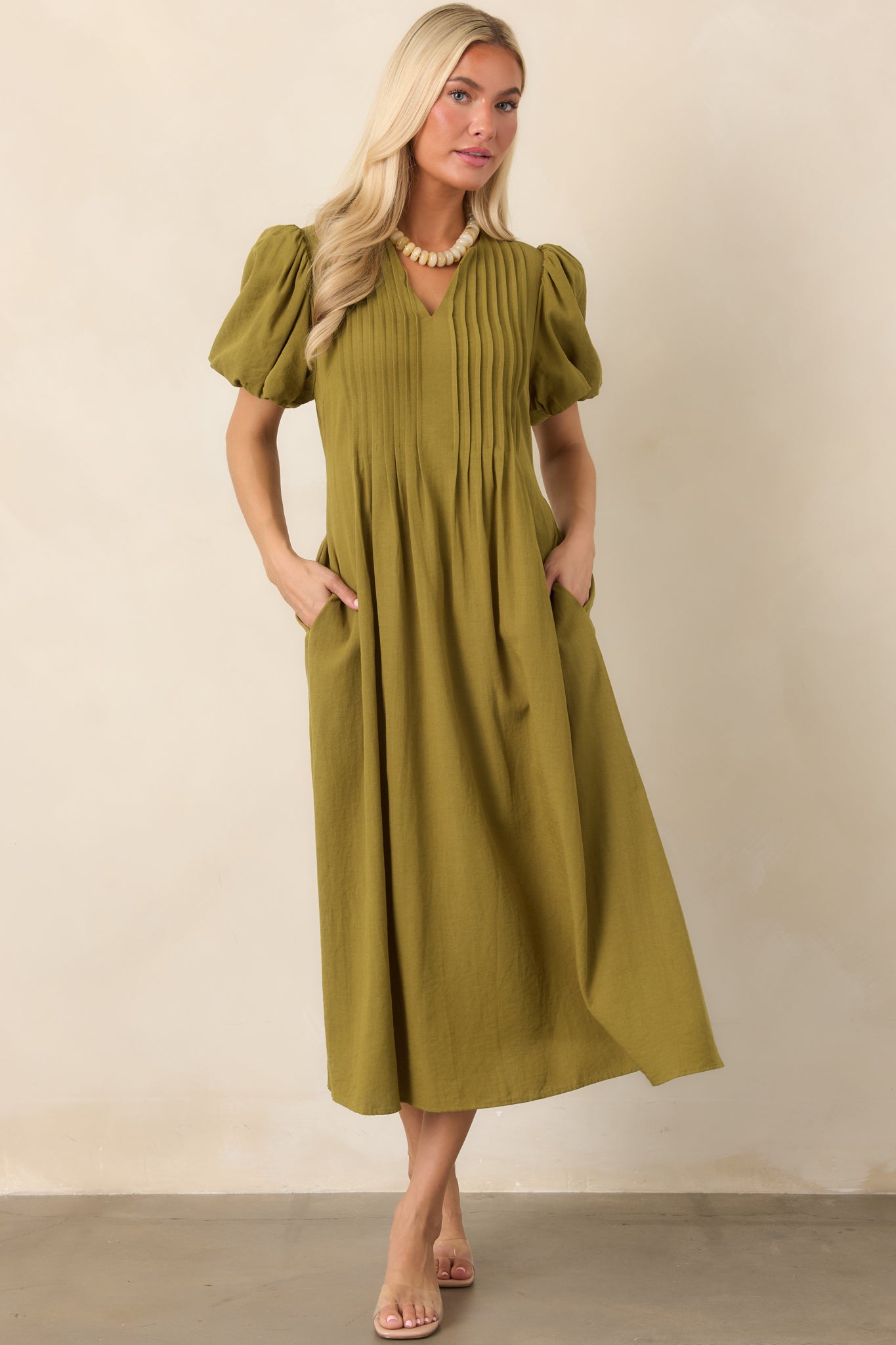 Rayon-nylon blend midi dress featuring a relaxed V-neck, structured pintucks, voluminous puff sleeves, side pockets, and an easy flowing silhouette.