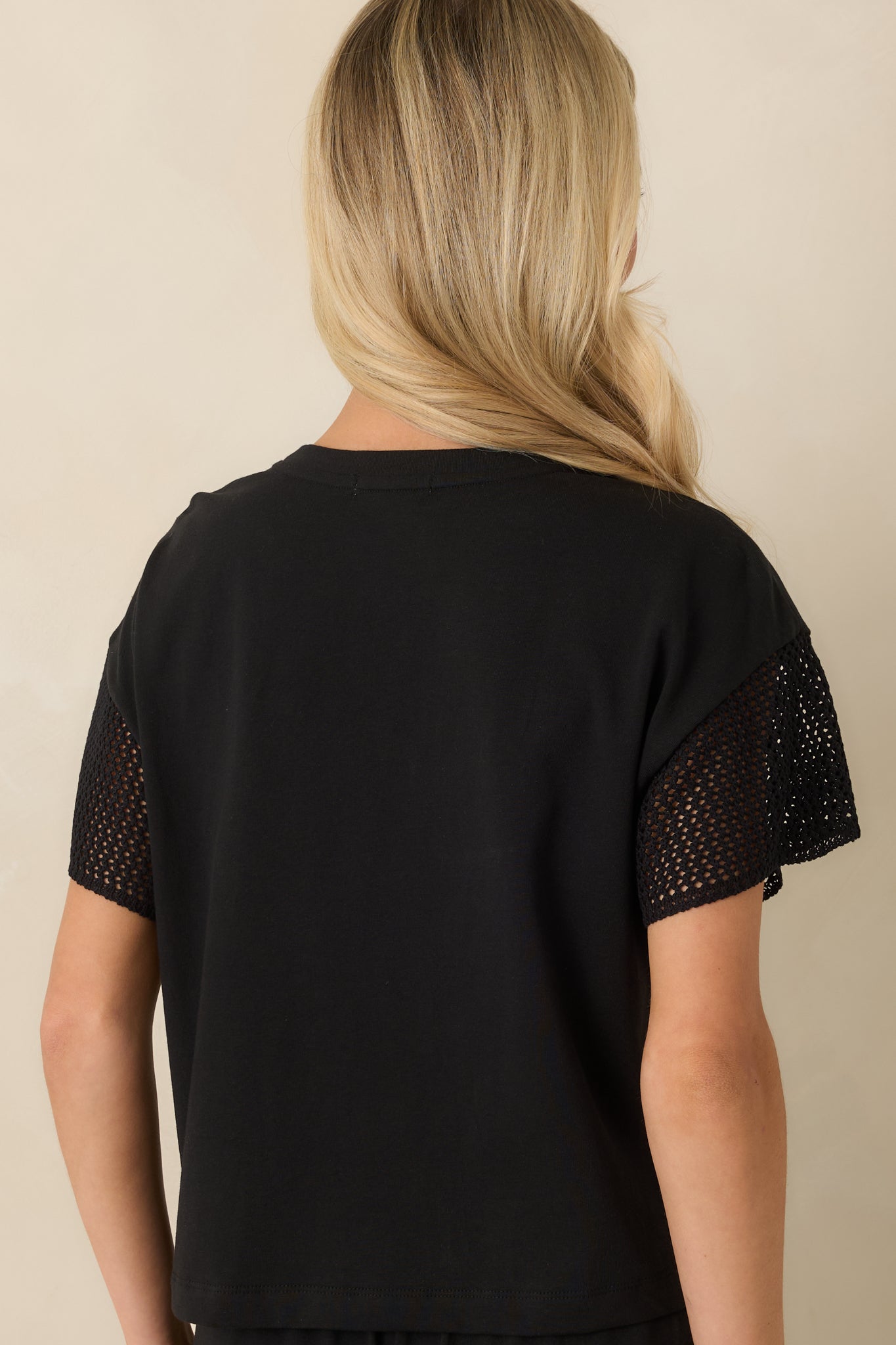 Rear view of the black cropped top showcasing the relaxed boxy silhouette, soft fabric, and clean back finish.