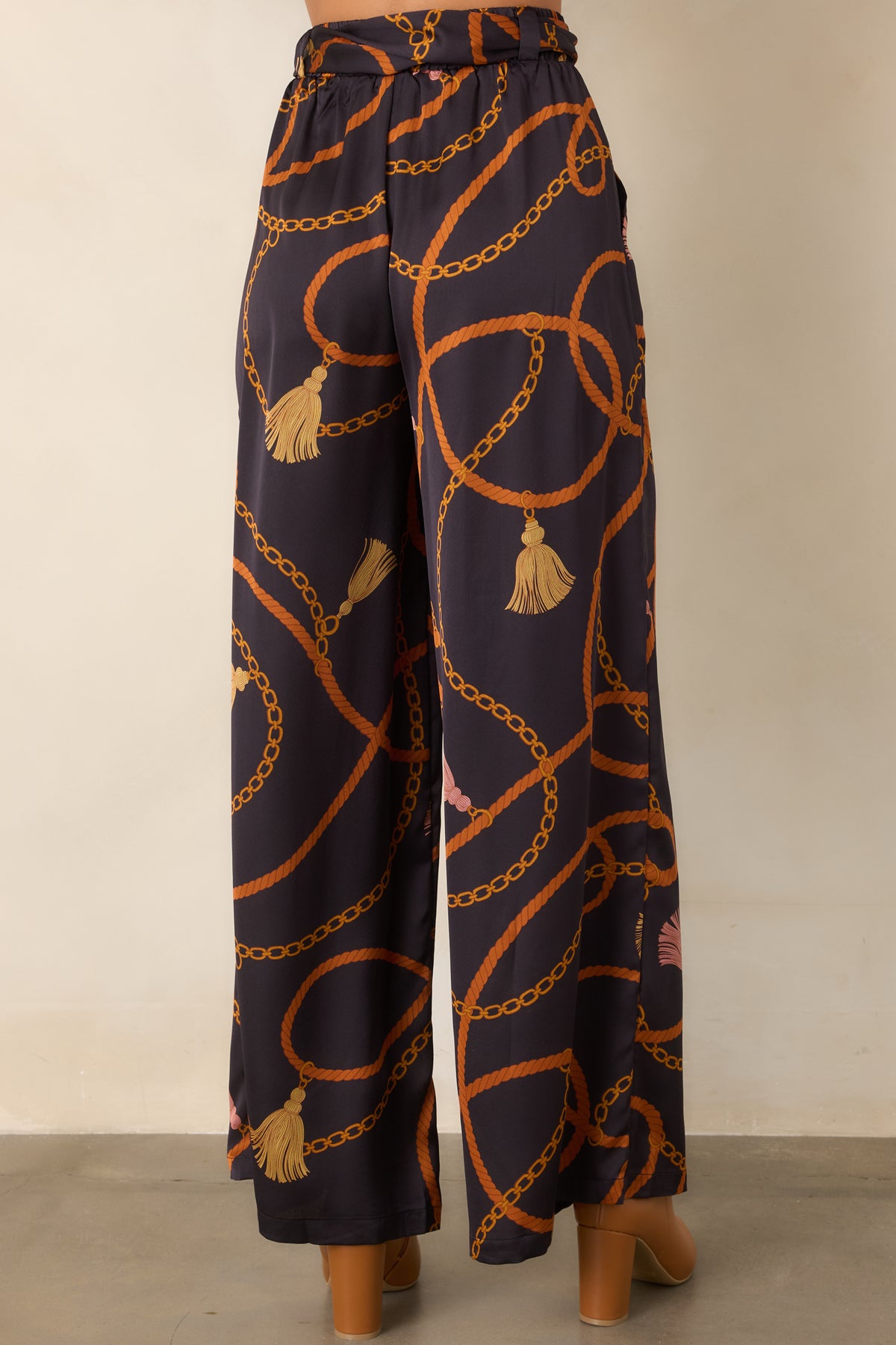 Rear of the black satin-feel wide-leg pants featuring the allover rope and chain print and coordinating scarf-tie belt.