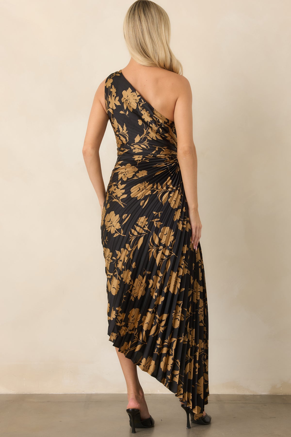 Rear view shows the golden floral pattern continuing across the black satin dress and asymmetrical high-low skirt.