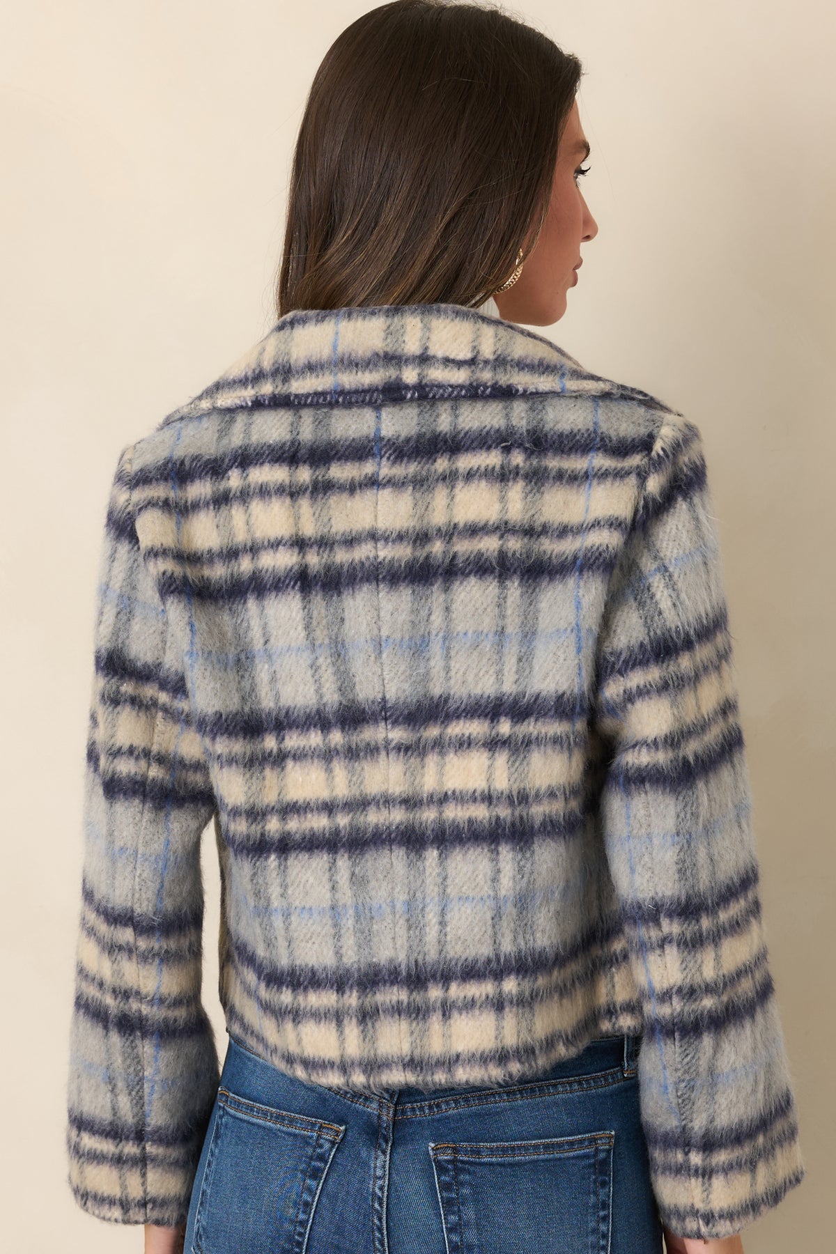 Rear view of the blue, navy, and ivory plaid jacket showing its cropped boxy silhouette, relaxed sleeves, and wide cuffs.