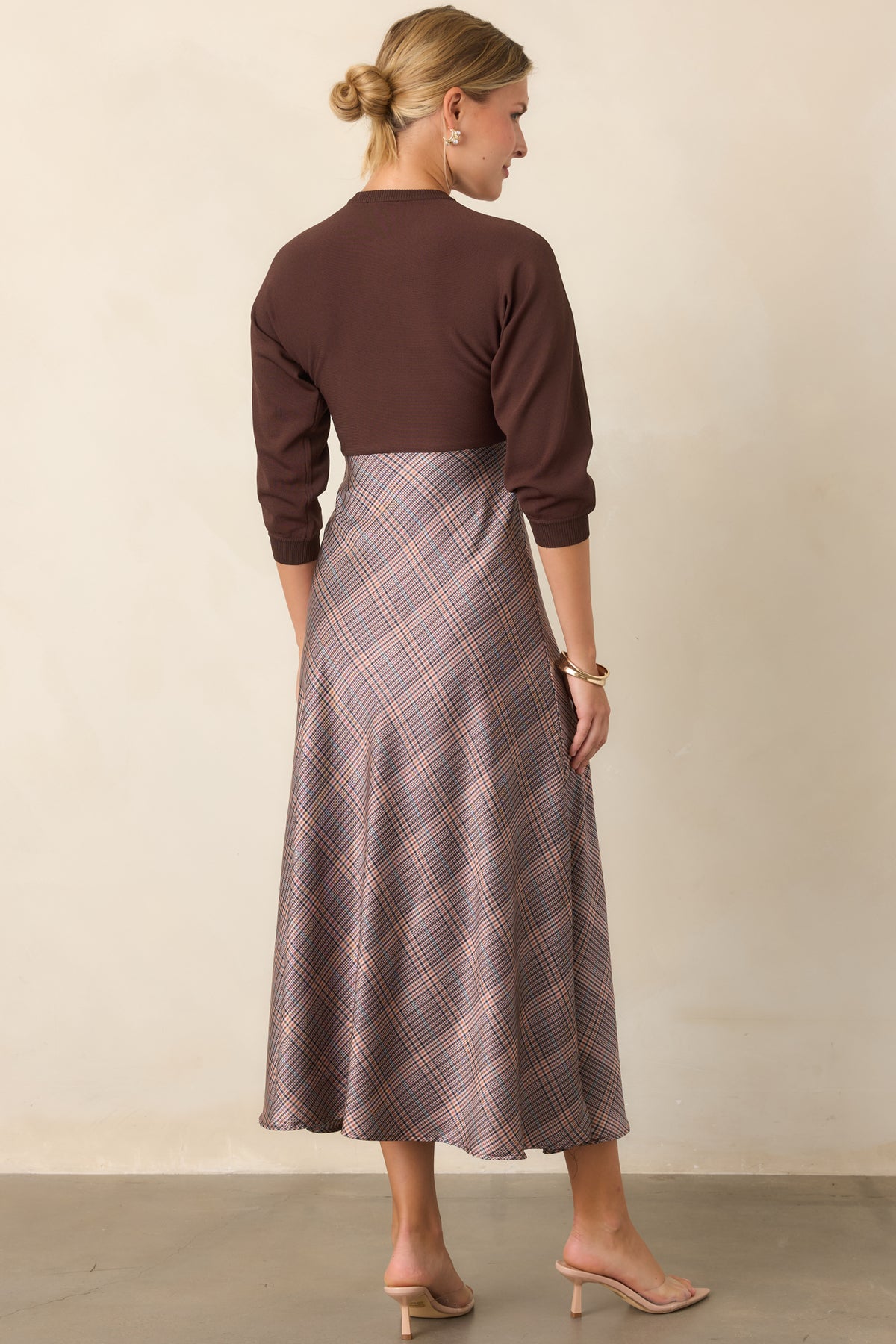 Rear view of the brown knit dress showing its fitted knit bodice and three-quarter sleeves.