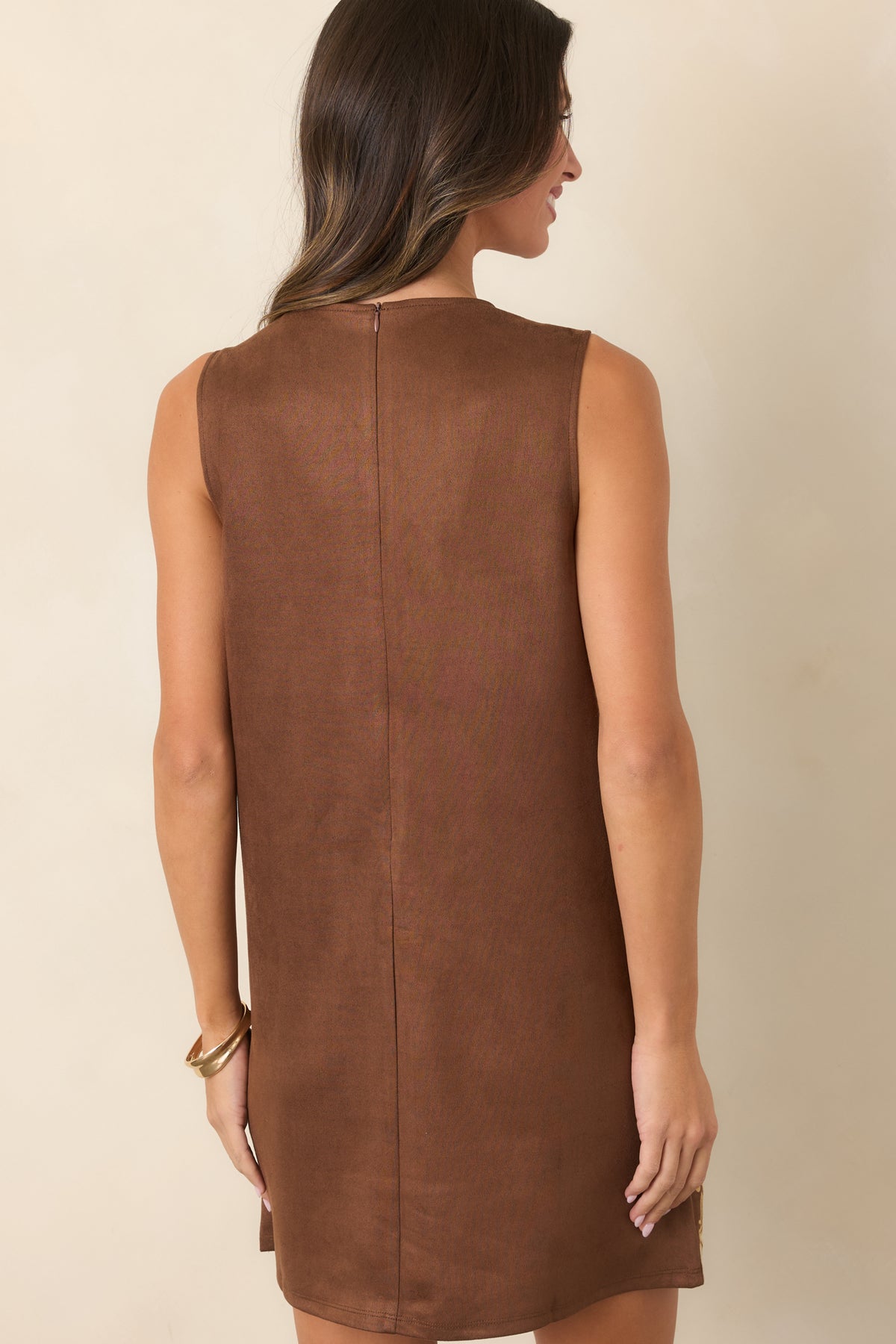 Rear of the brown sleeveless mini dress featuring a solid fabric finish, round neckline, and concealed back zipper.