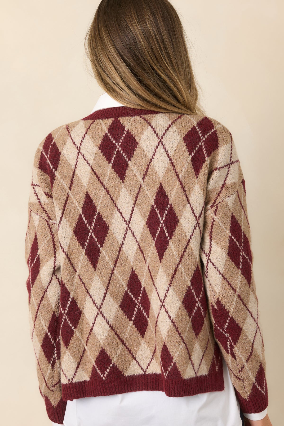 The rear of the sweater continues the allover burgundy and neutral argyle pattern with a ribbed hem.