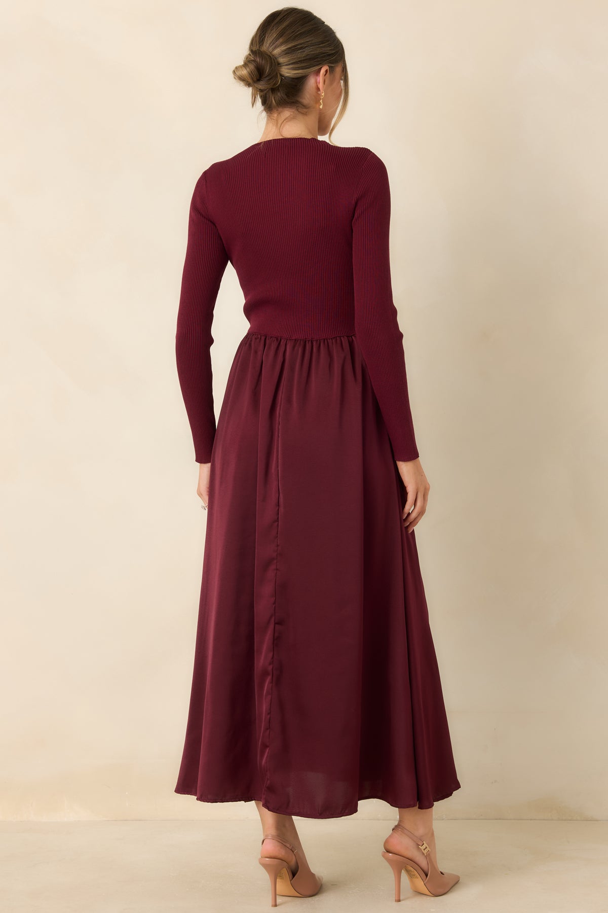Rear of the burgundy fit-and-flare dress showing the long-sleeve ribbed knit bodice and flowing satin skirt.