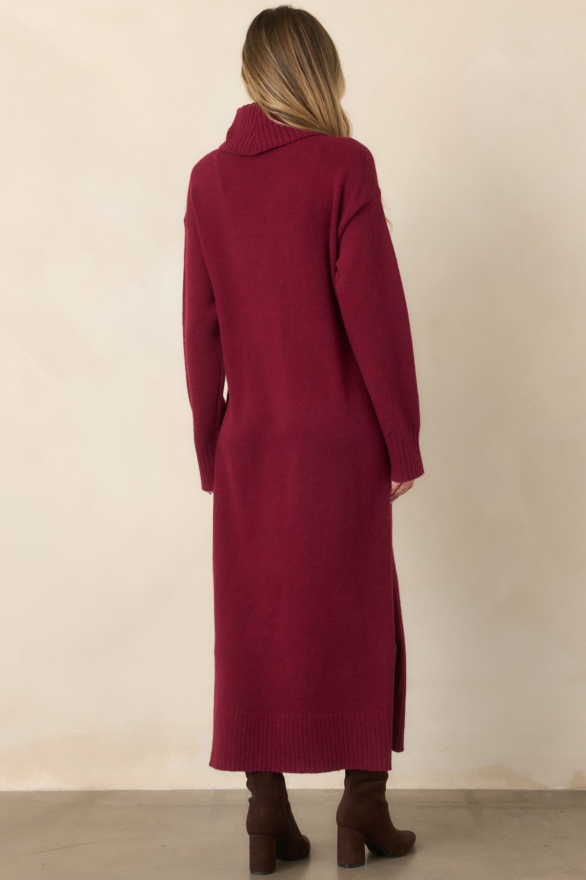 Rear view of the burgundy knit sweater dress showcasing its turtleneck, long sleeves, relaxed midi silhouette, and ribbed hem and cuffs.