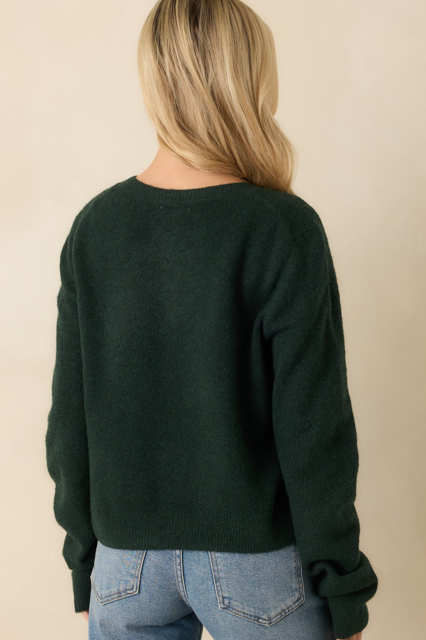 Back view of the cardigan showing smooth knit fabric, relaxed fit, and ribbed trim at hem and cuffs.