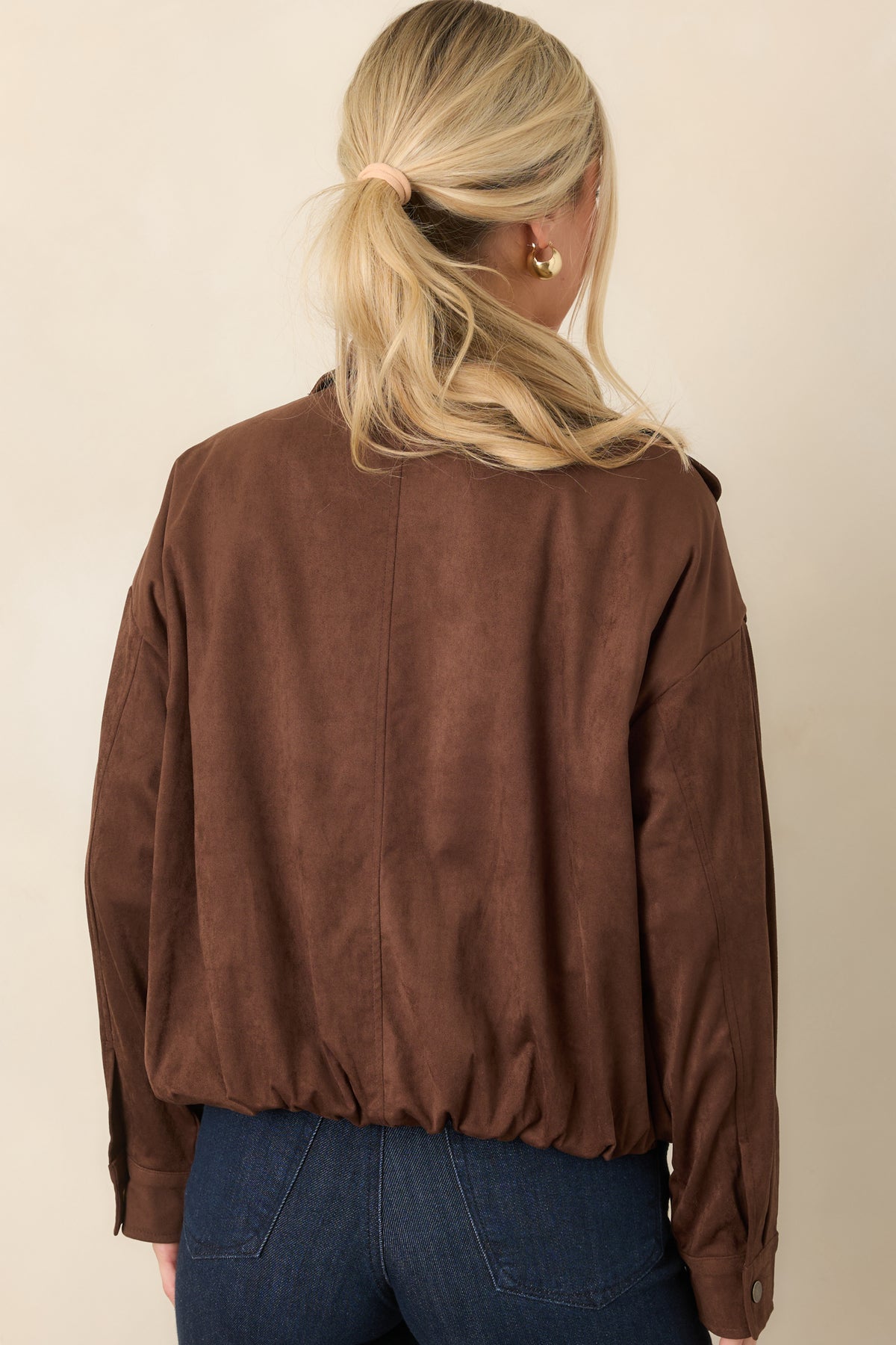 Rear of the chocolate faux suede bomber showing its dropped shoulders, roomy sleeves, and elasticized hem.