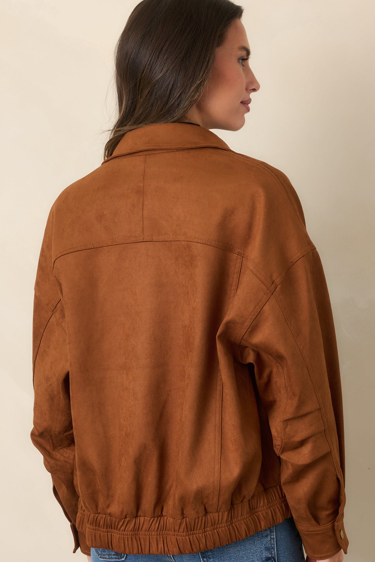 Rear of the cognac faux suede bomber jacket showing its dropped shoulders, roomy sleeves, and elasticized hem.