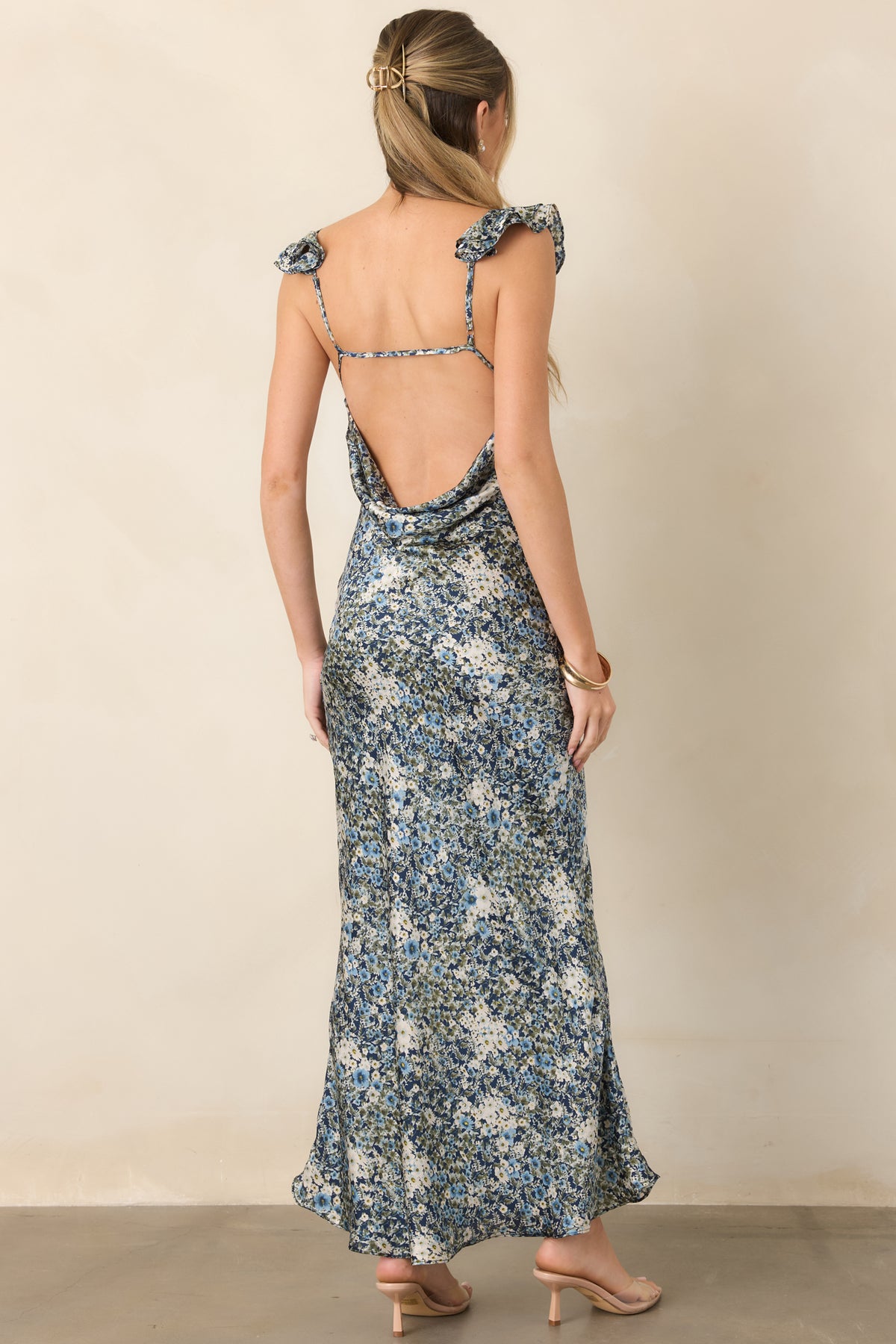 Rear of the deep blue floral satin dress featuring an open back, soft cowl drape, and slender support strap.