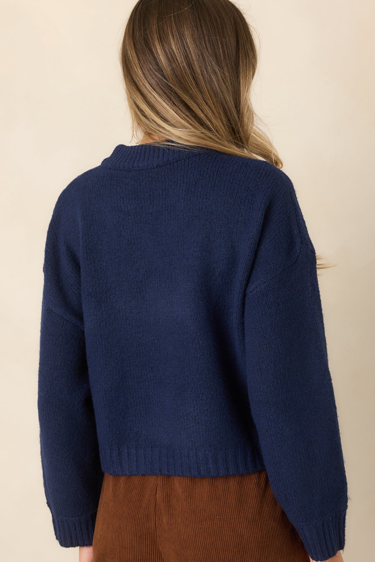 Rear of the deep navy knit pullover showing its dropped shoulders, roomy long sleeves, boxy silhouette, and ribbed hem.
