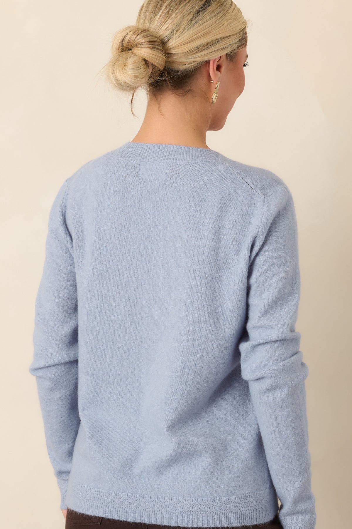 Rear view of the dusty blue knit top featuring long sleeves and a ribbed hem.