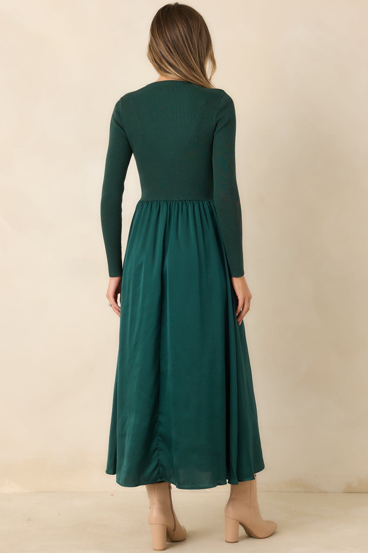 Rear view of the hunter green dress showing its fitted ribbed knit bodice, long sleeves, and flowing satin skirt.