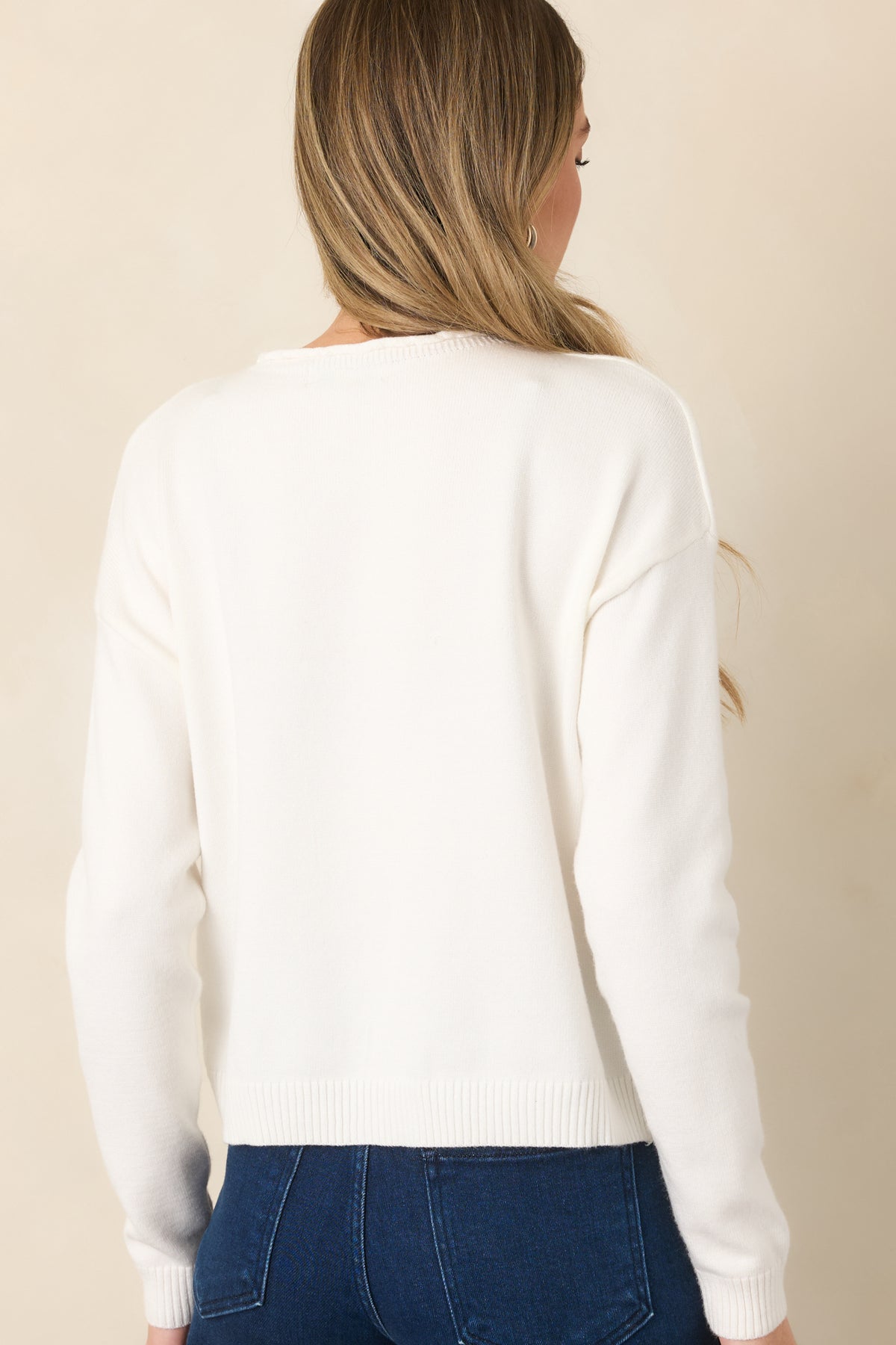 Rear of the ivory knit top showing its dropped shoulders, relaxed shape, and ribbed hem.