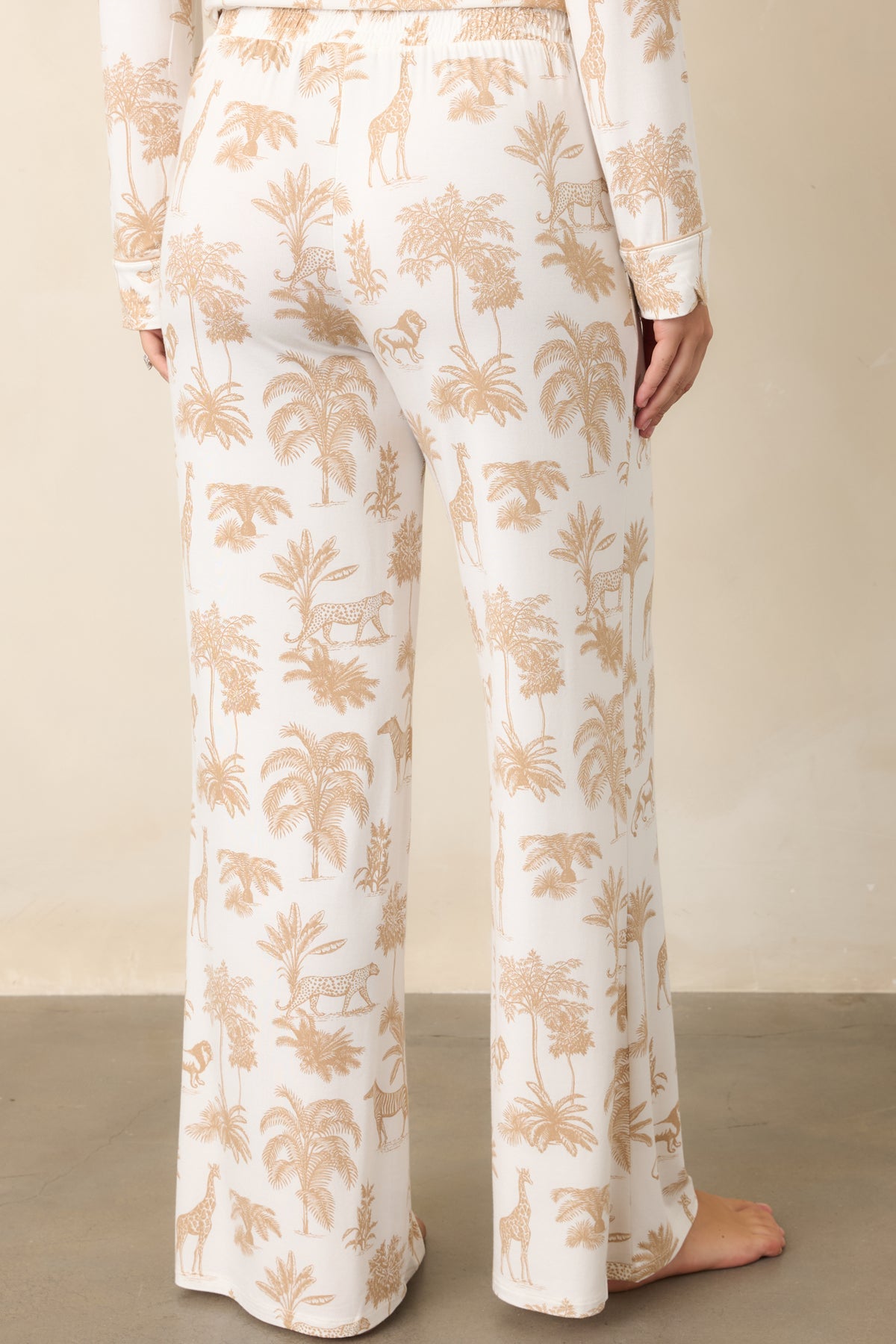 Rear view shows the safari animal and tropical foliage print continuing across the relaxed ivory pants and full-length legs.