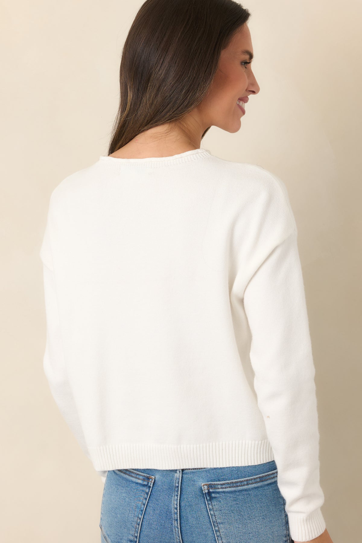 Rear view highlights the shorter length, long sleeves, and clean ribbed finish of the ivory top.