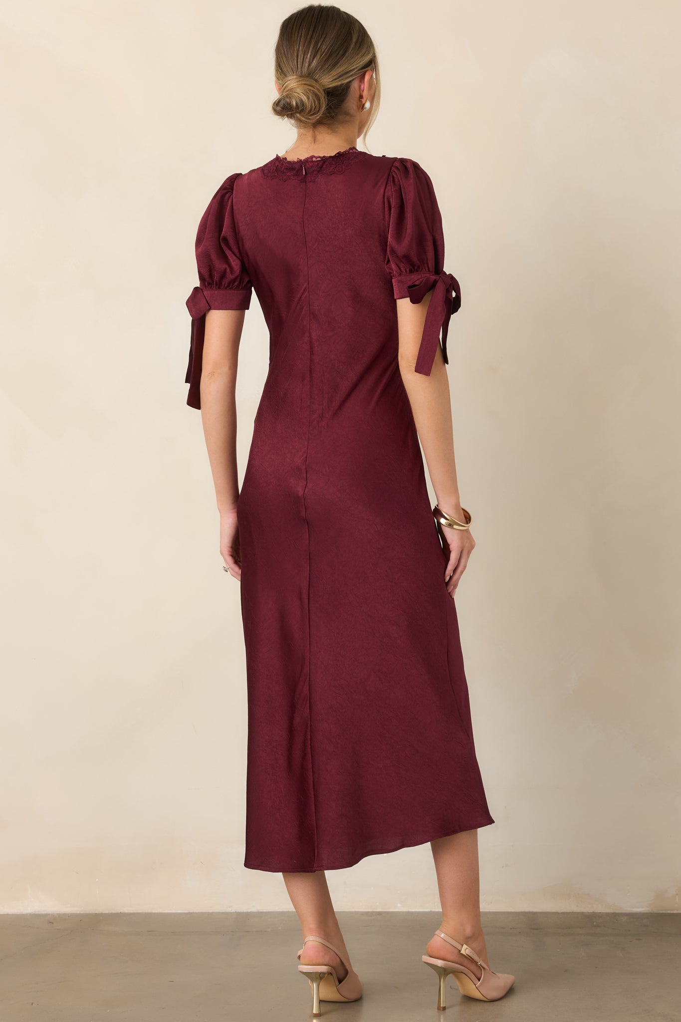 Rear view of the jewel-tone satin midi dress showcasing the fluid skirt, puff sleeves, smooth lined finish, and concealed back zipper.