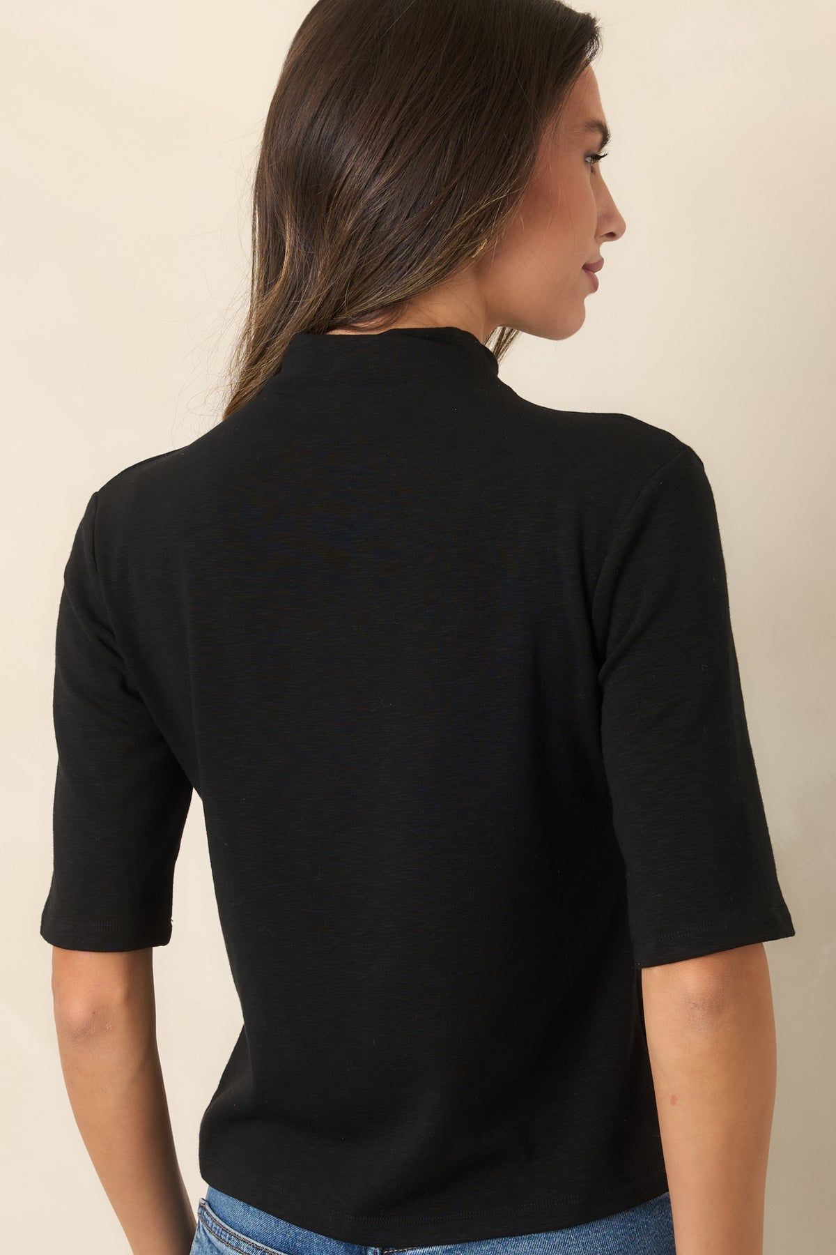 Rear of the knit top showing the high neckline, short sleeves, and clean streamlined silhouette.