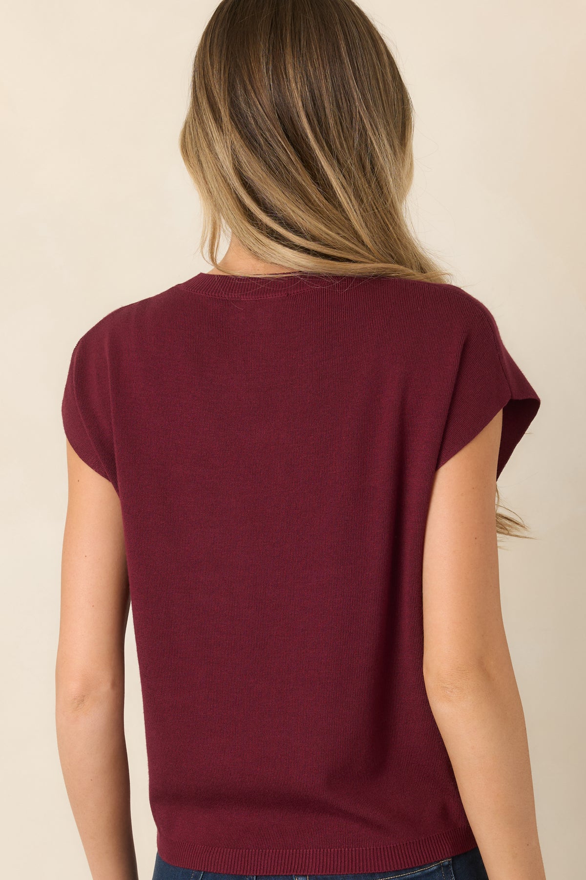 Rear view of the lightweight knit top showcasing its straight silhouette, relaxed short sleeves, and ribbed hem and neckline.