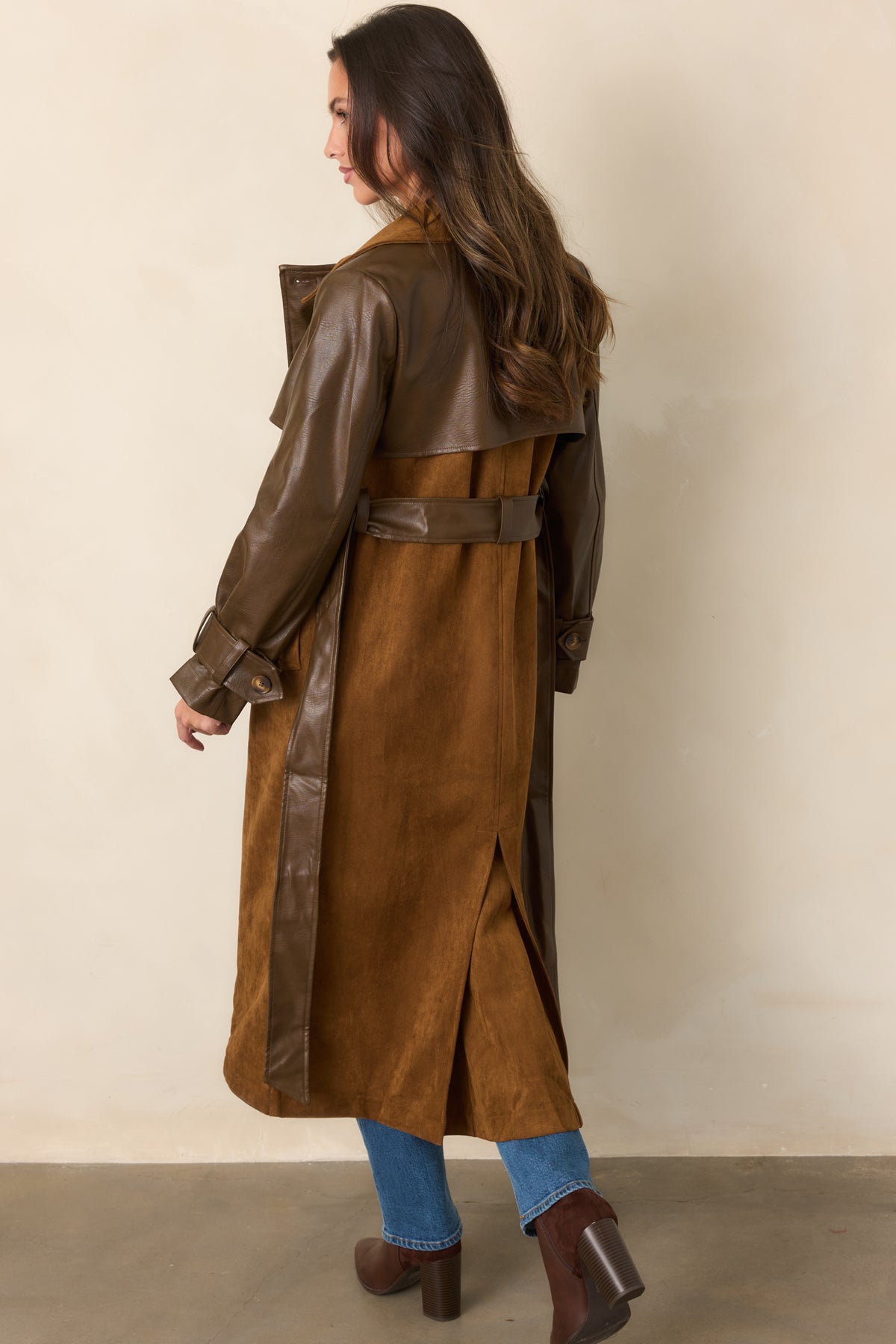 Rear view highlights the long trench silhouette, contrasting brown sleeves, and waist belt against the warm caramel body.