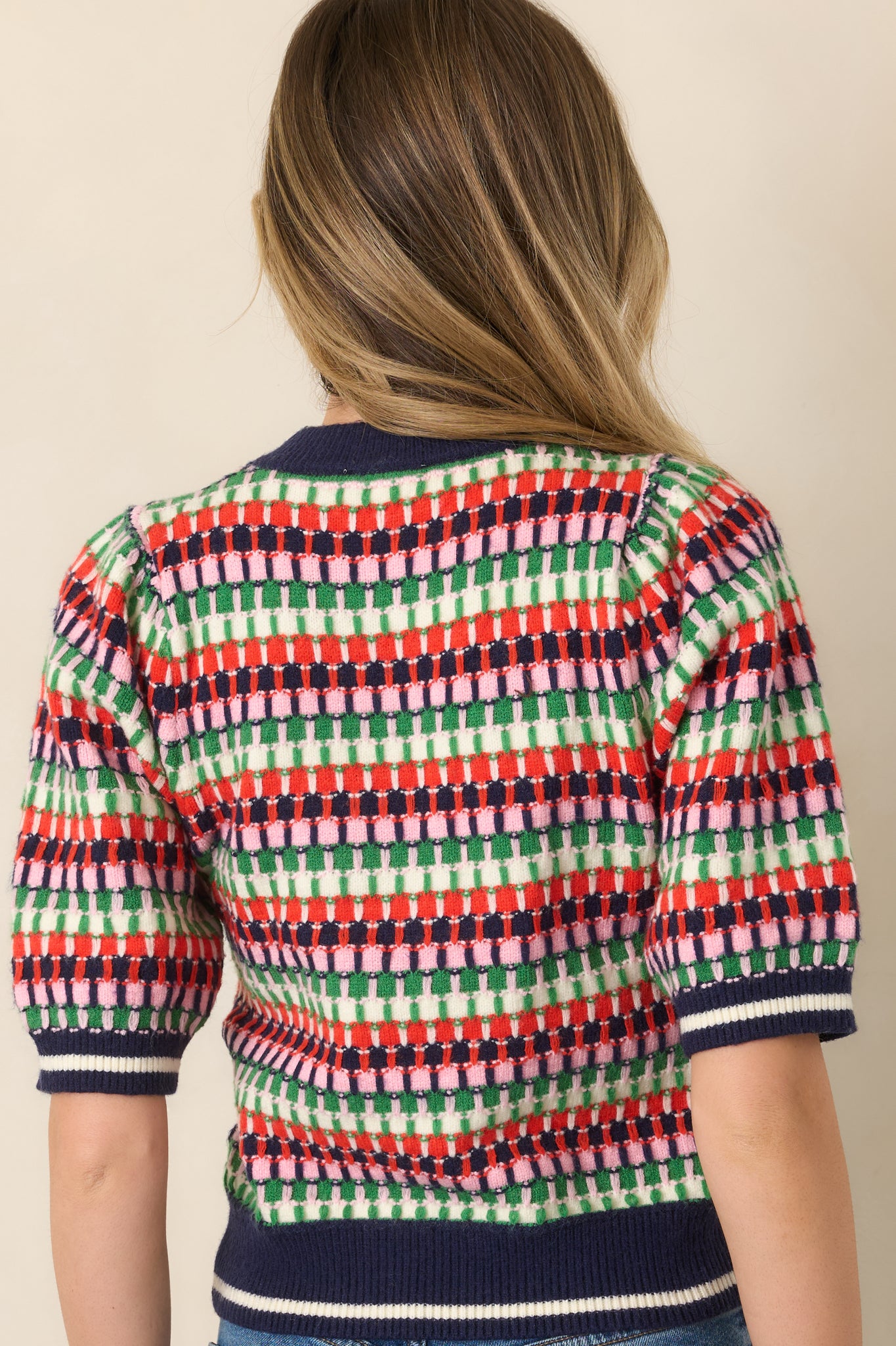 Rear view of the striped knit top featuring the multicolor pattern, short sleeves, crew neckline, and solid navy ribbed hem.