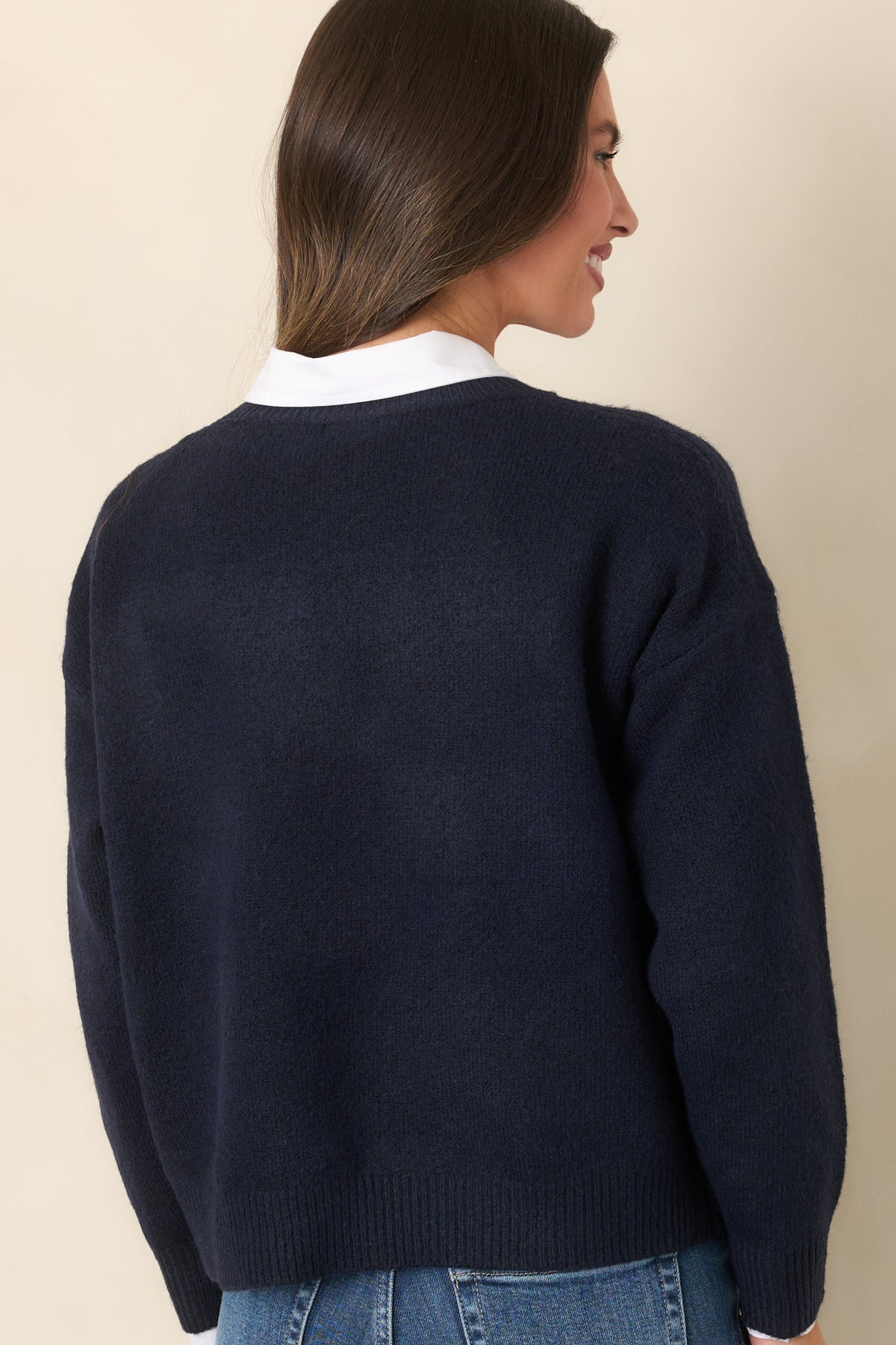 Rear of the deep navy knit pullover featuring a plain knit back, long sleeves, and ribbed neckline, cuffs, and hem.
