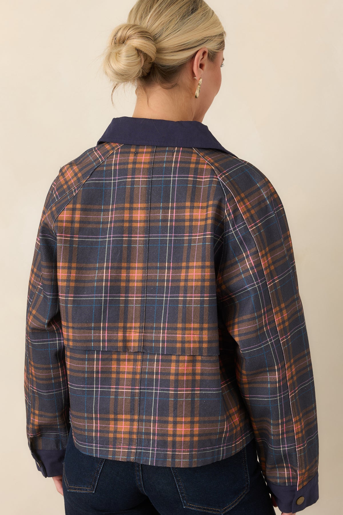 Rear of the relaxed navy plaid jacket showing the multicolor check pattern, raglan sleeves, and solid navy cuffs.