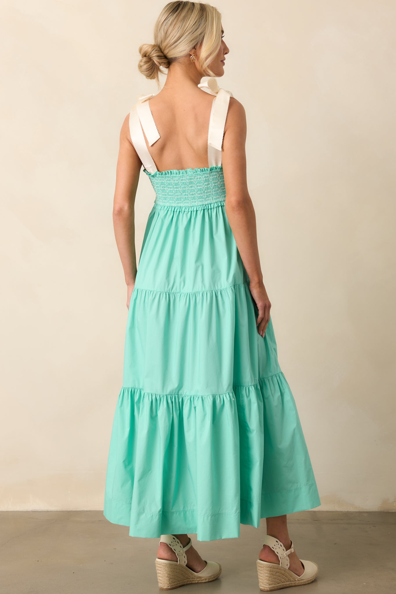 The rear of this mint green midi dress showcases the adjustable self-tie bow straps and a relaxed, flowing fit.