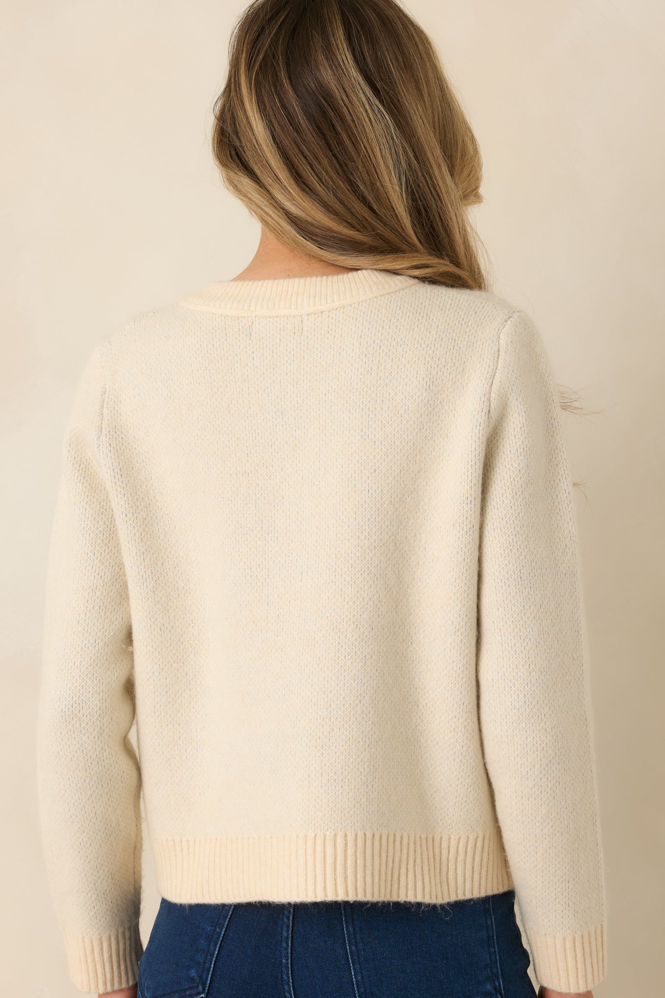 Rear of the natural multi argyle cardigan showing continuous argyle knit pattern and clean, ribbed hemline.