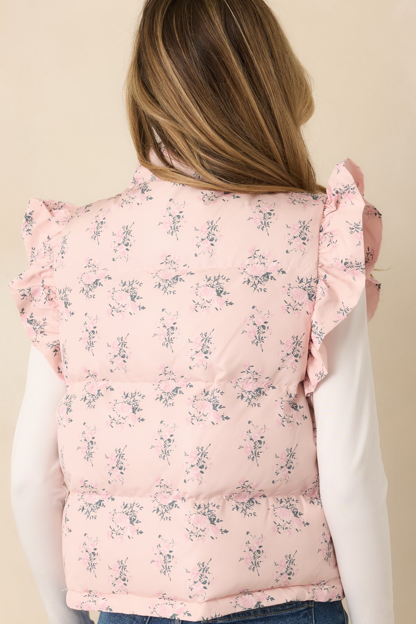 Rear of the blush pink puffer vest showing continuous quilted floral pattern and smooth, lightly padded back panel.