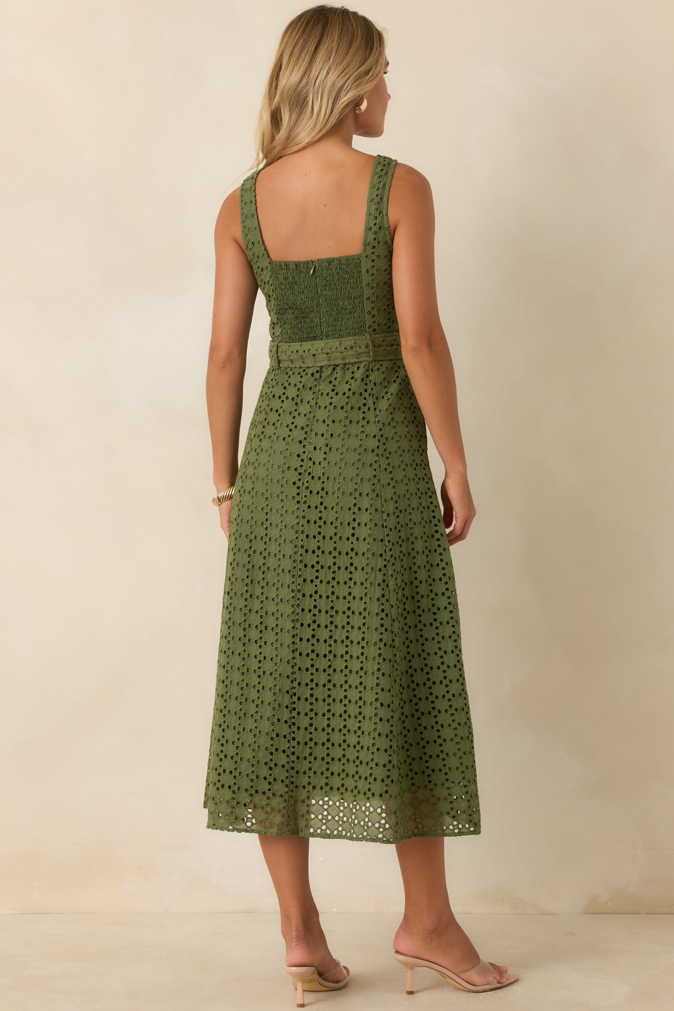 Rear view of the olive green cotton eyelet midi dress highlighting the sleeveless design, embroidered fabric, and flattering belted silhouette.
