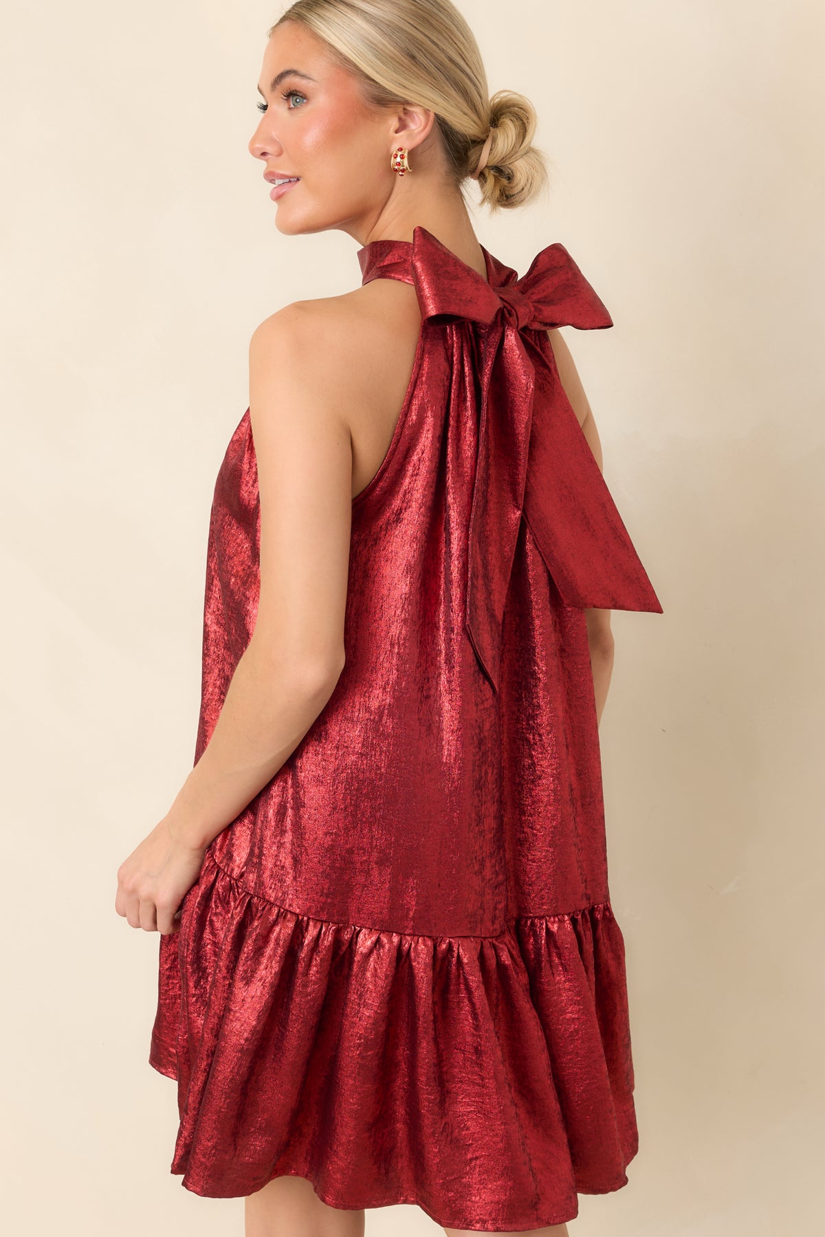 Rear view of the red halter mini dress featuring an oversized back tie bow and flowing swing silhouette.