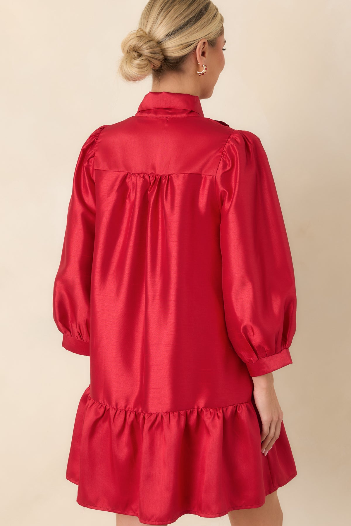 Rear view of the red mini dress featuring a gathered back yoke, three-quarter puff sleeves, and a ruffled hem.