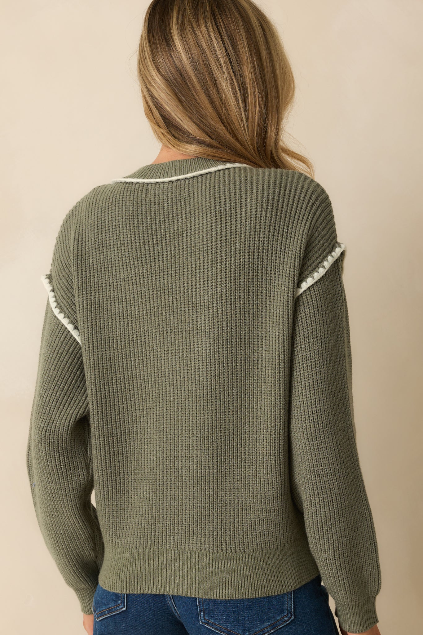 Rear view of the ribbed knit sage green cardigan with long sleeves and subtle white trim along the edges.