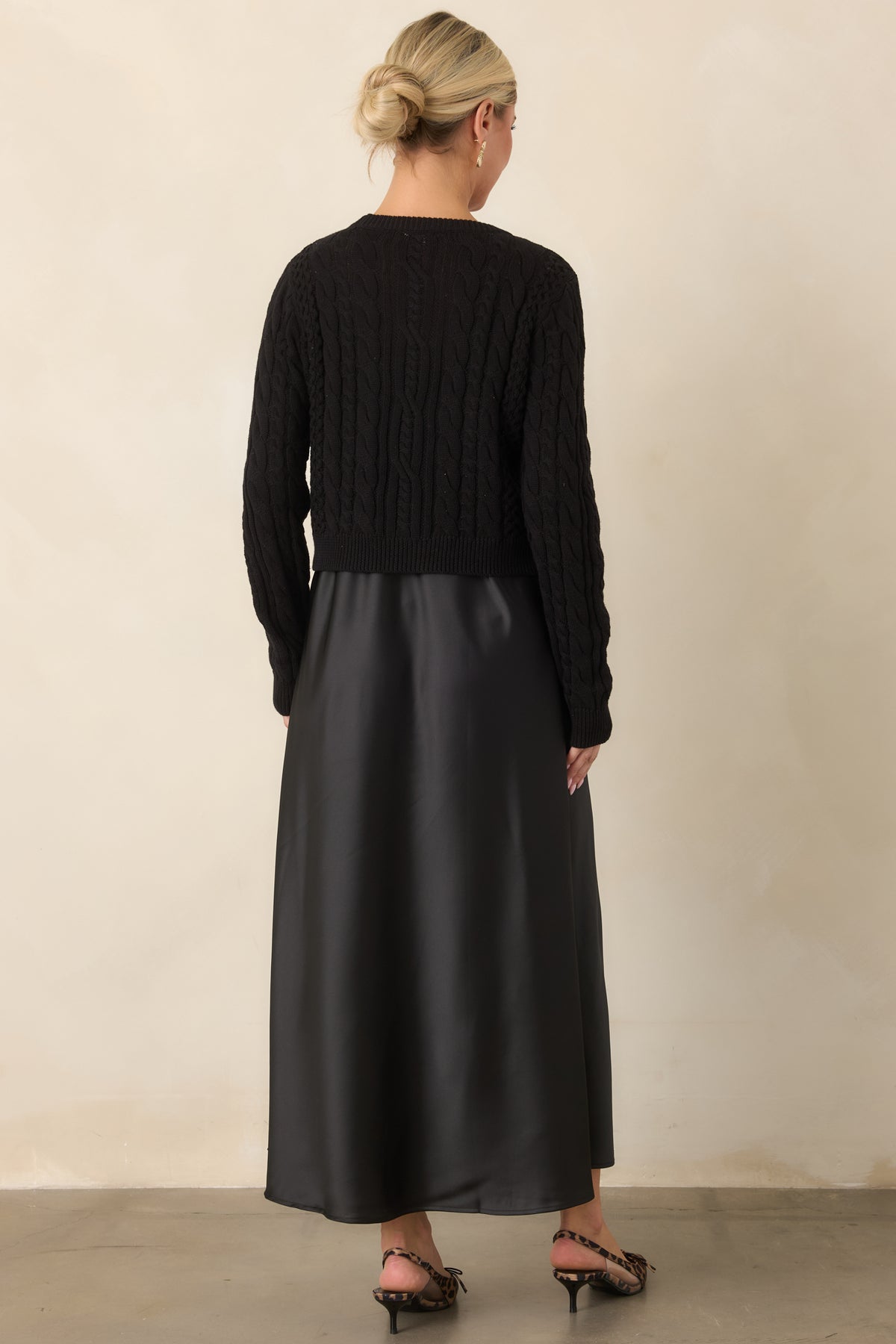 Rear view shows the fluid satin maxi dress and textured cropped sweater creating a softly layered silhouette.