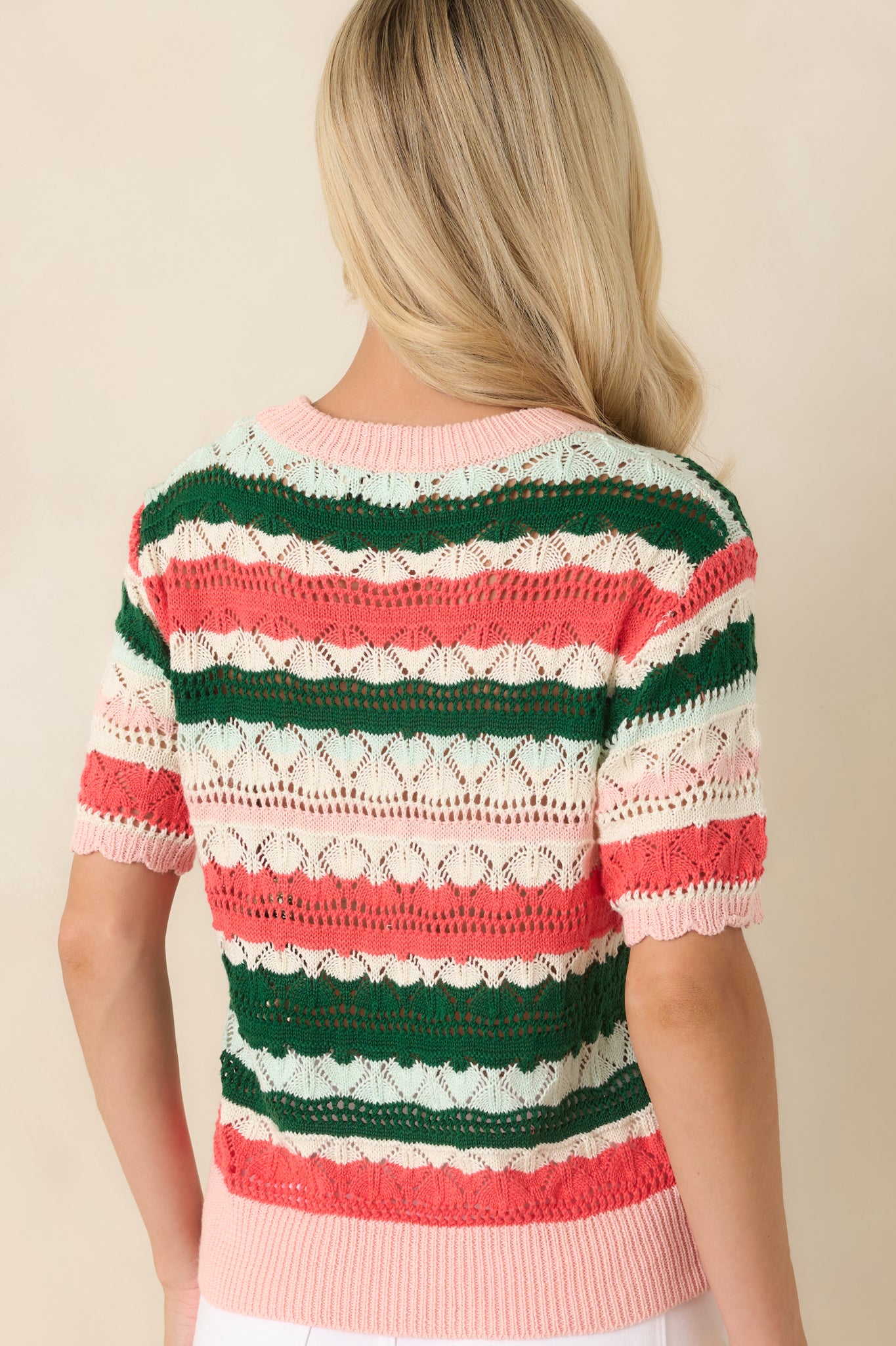 Rear view of the lightweight striped knit top featuring alternating green, coral, blush pink, and ivory stripes with a relaxed silhouette.