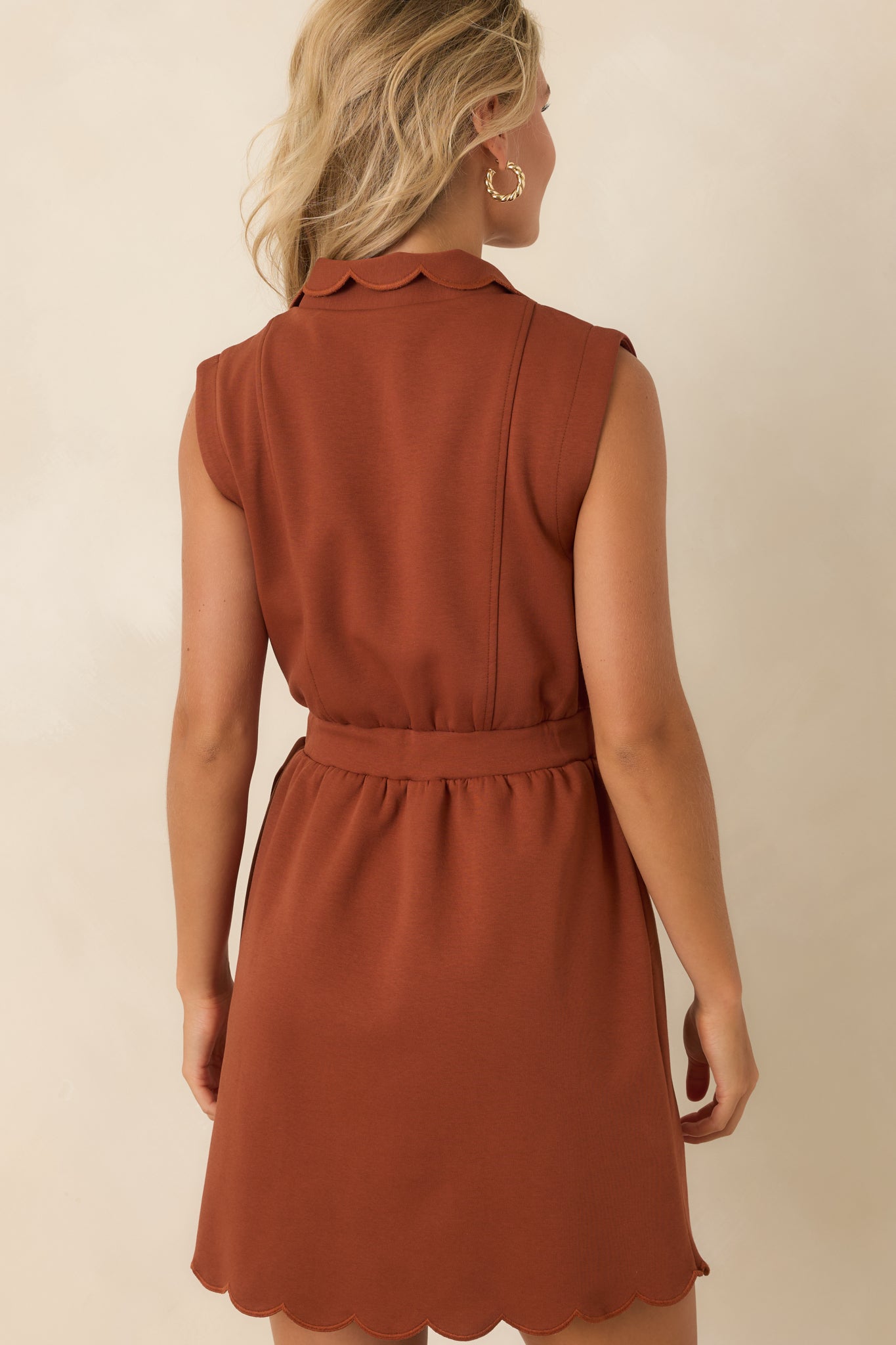 Rear view of the structured mini dress highlighting the tailored fit, cap-style shoulders, and scalloped hem.