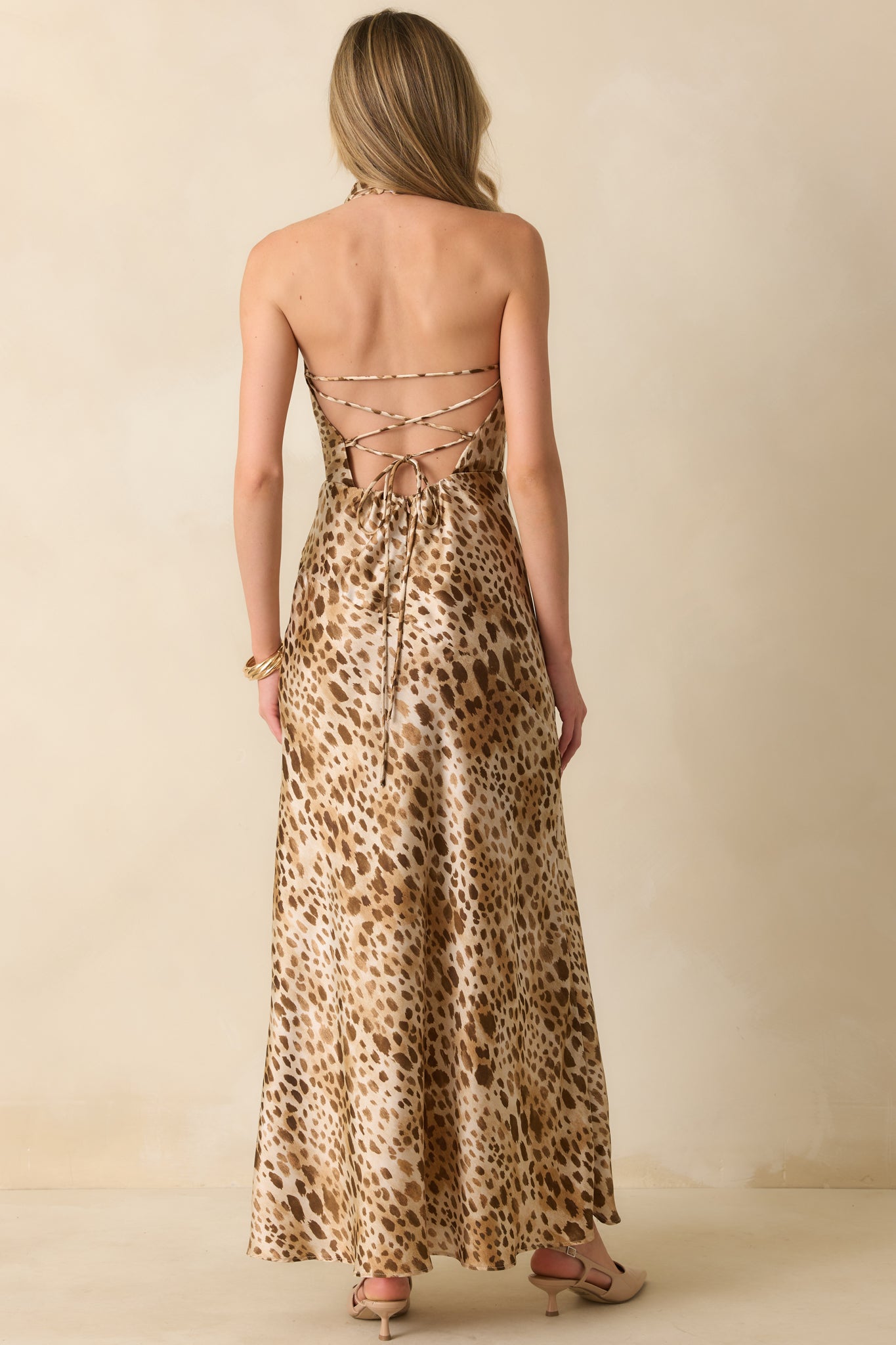 Rear of tan leopard print dress featuring open lace-up tie closure and hidden zipper, with the flowing bias-cut skirt and mini lining visible.