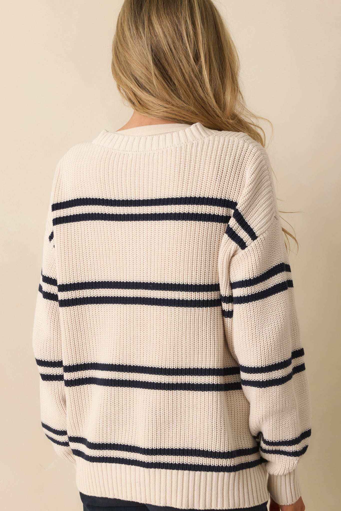Rear view of the ivory cardigan showing smooth knit back, long sleeves, and ribbed hems.
