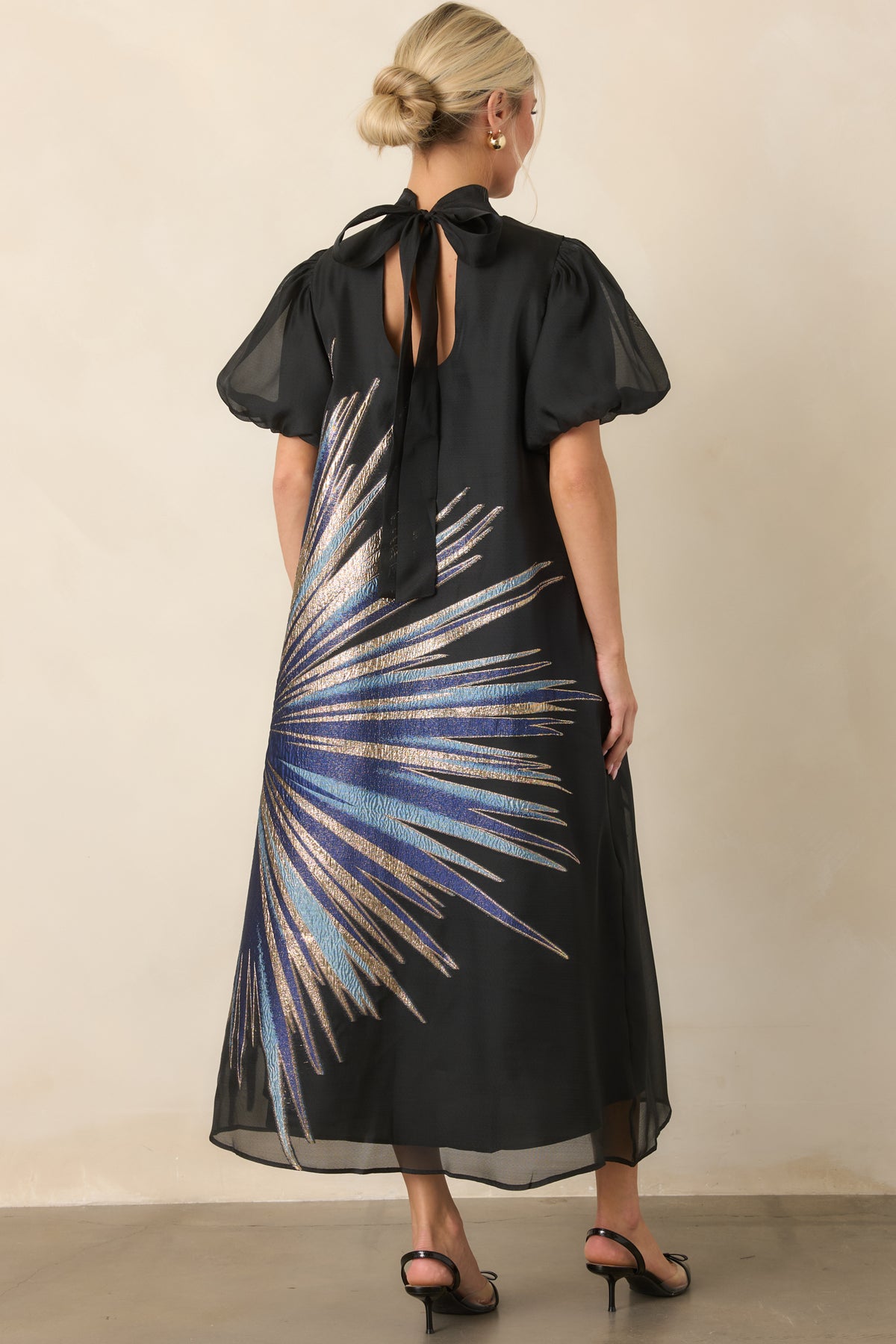Rear view highlighting the back keyhole closure with long ties and sheer puff sleeves.