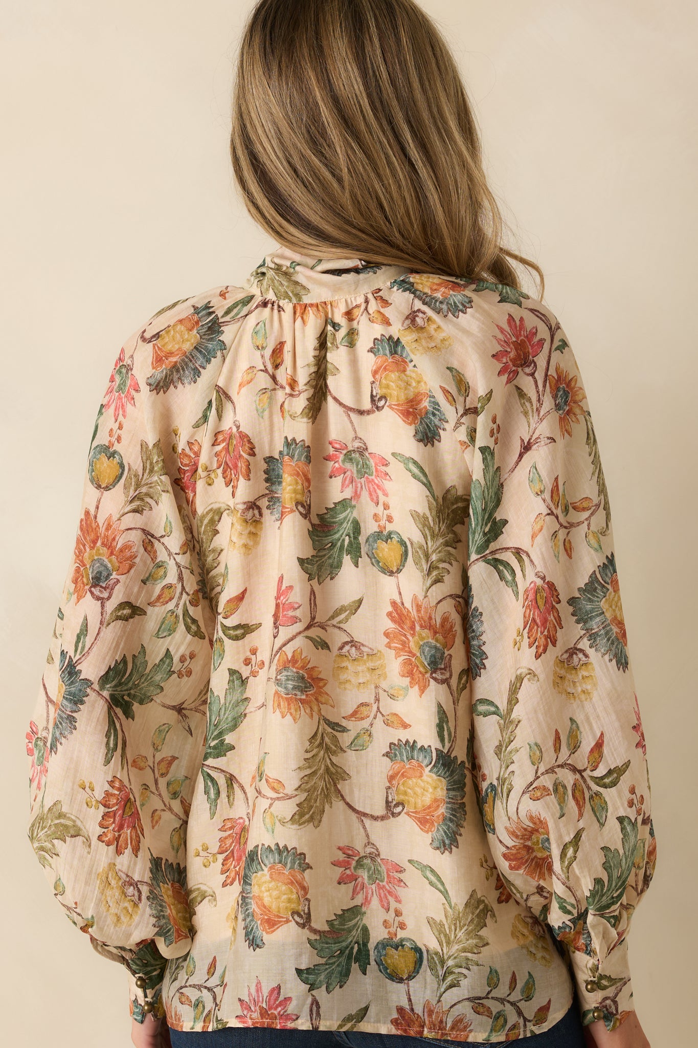 Rear view of the beige floral blouse, showing the relaxed fit and long balloon sleeves.