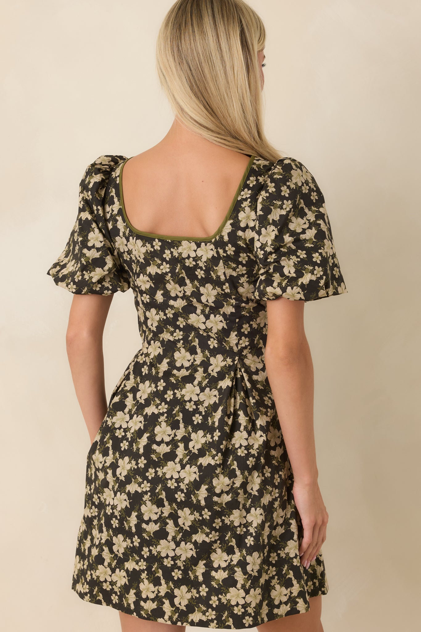Rear view of the black floral mini dress highlighting the puff sleeves, fit-and-flare shape, and clean back silhouette.