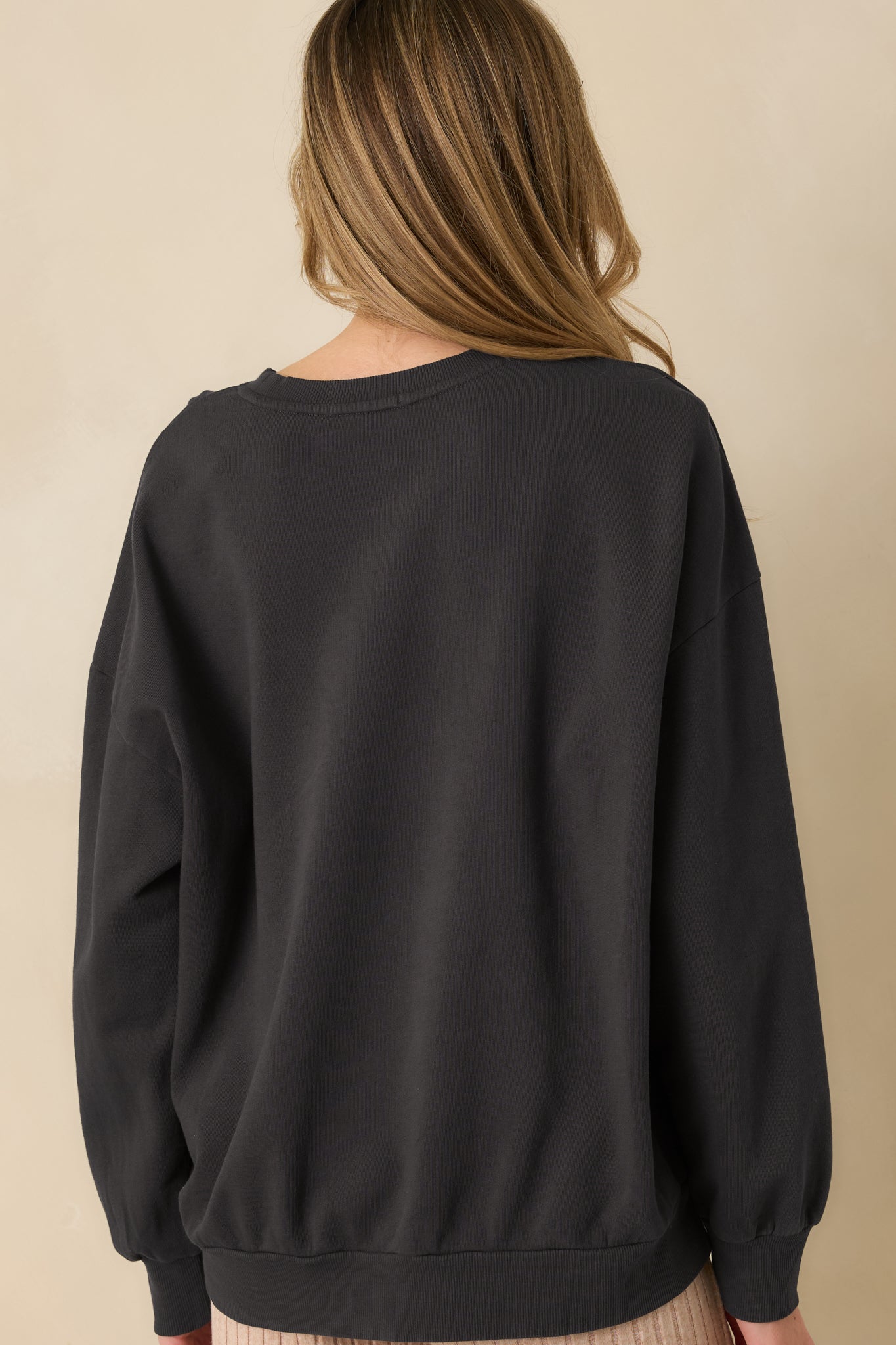 Rear view of the black sweatshirt showing relaxed silhouette and ribbed hem and cuffs.