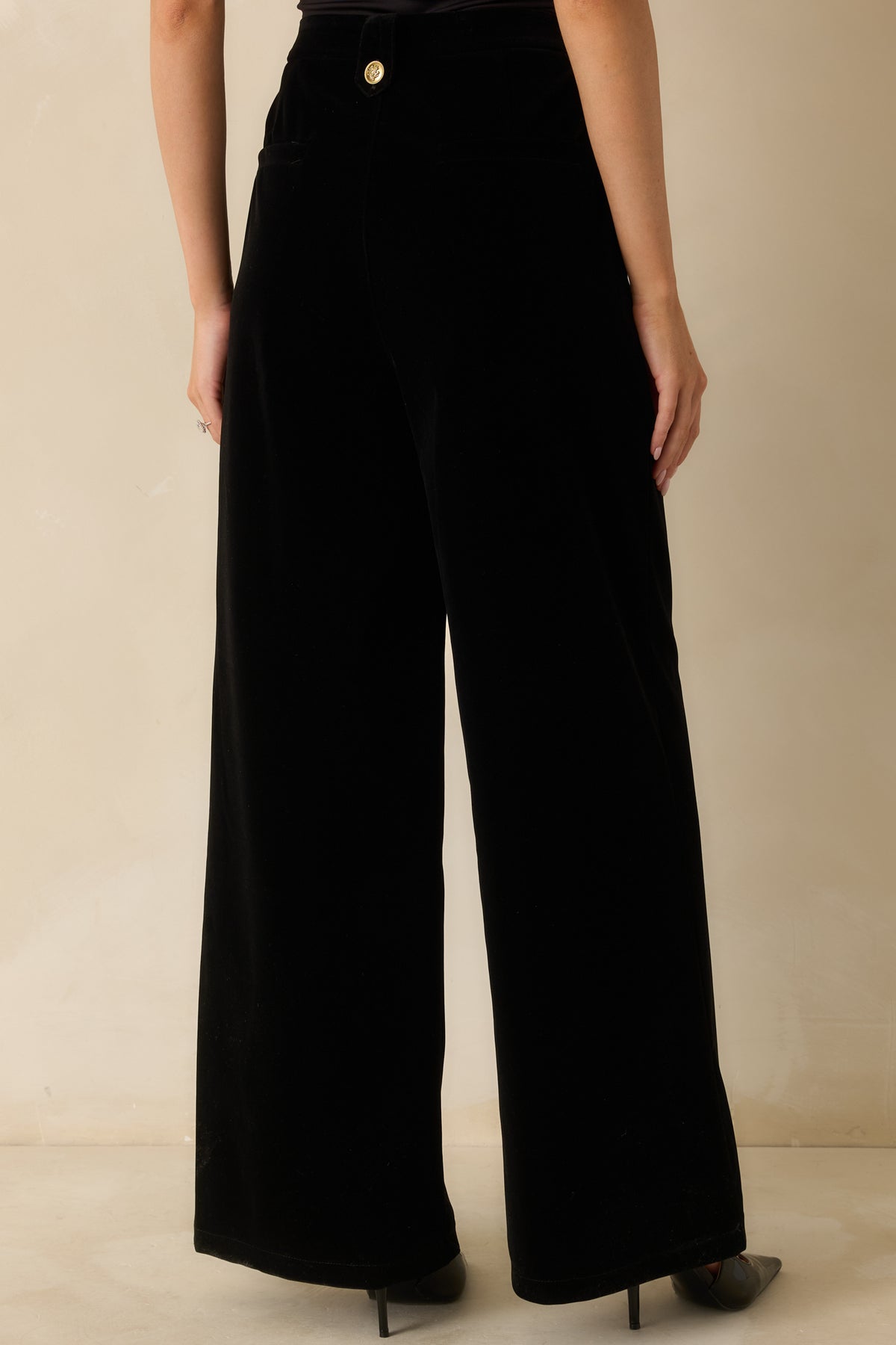 Rear view of the black velvet pants showing the high-rise waist and back zipper closure.