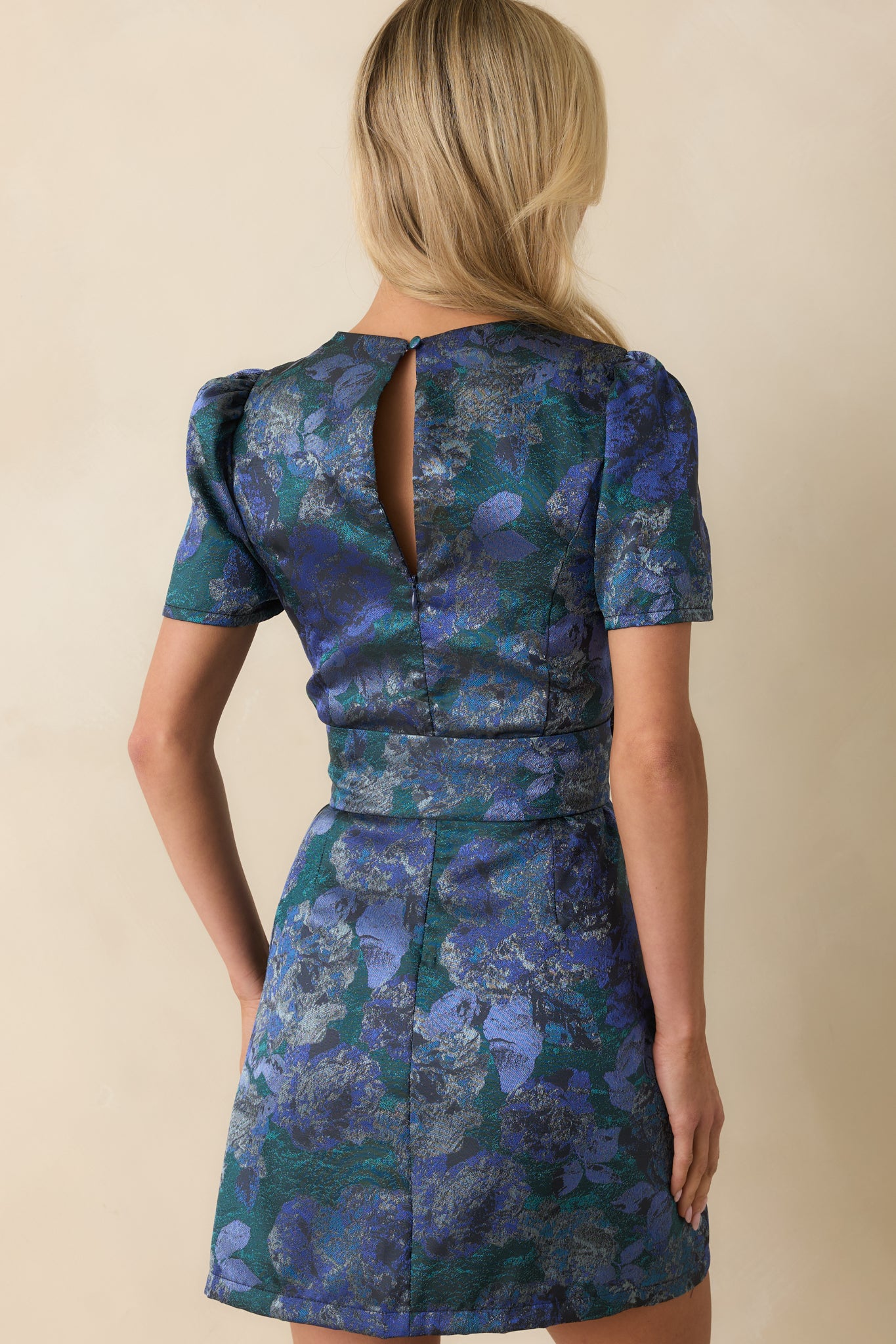 Rear view of the blue mini dress showing the concealed zipper, back keyhole button closure, and sash belt.