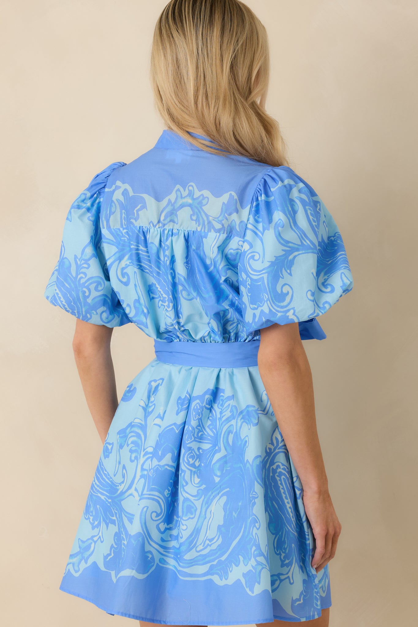 Rear view of the blue paisley mini dress showing the relaxed fit and smooth cotton drape through the silhouette.