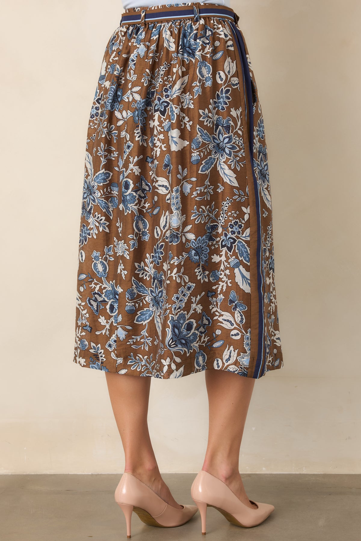 Rear view of the brown floral midi skirt showcasing its striped border, high-rise waistband, coordinating belt, and flowing A-line shape.